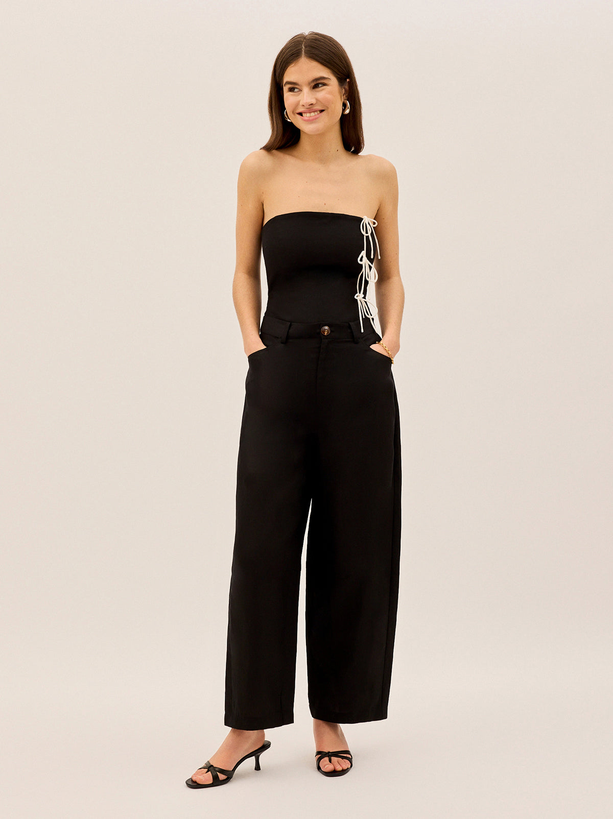 Andie Black Linen Blend Barrel Trousers by Kitri Studio. Say hello to Andie, your new go-to trousers for effortless style and modern tailoring.  Designed with a mid-rise waist and a barrel-leg silhouette, these trousers offer a relaxed yet structured fit that feels as good as it looks. Button and zip fly front. Slanted pockets. Loose fit. Shell: 80%% Lenzing Tencel™ Lyocell 20%% Linen Lining: 100%% Recycled Polyester.