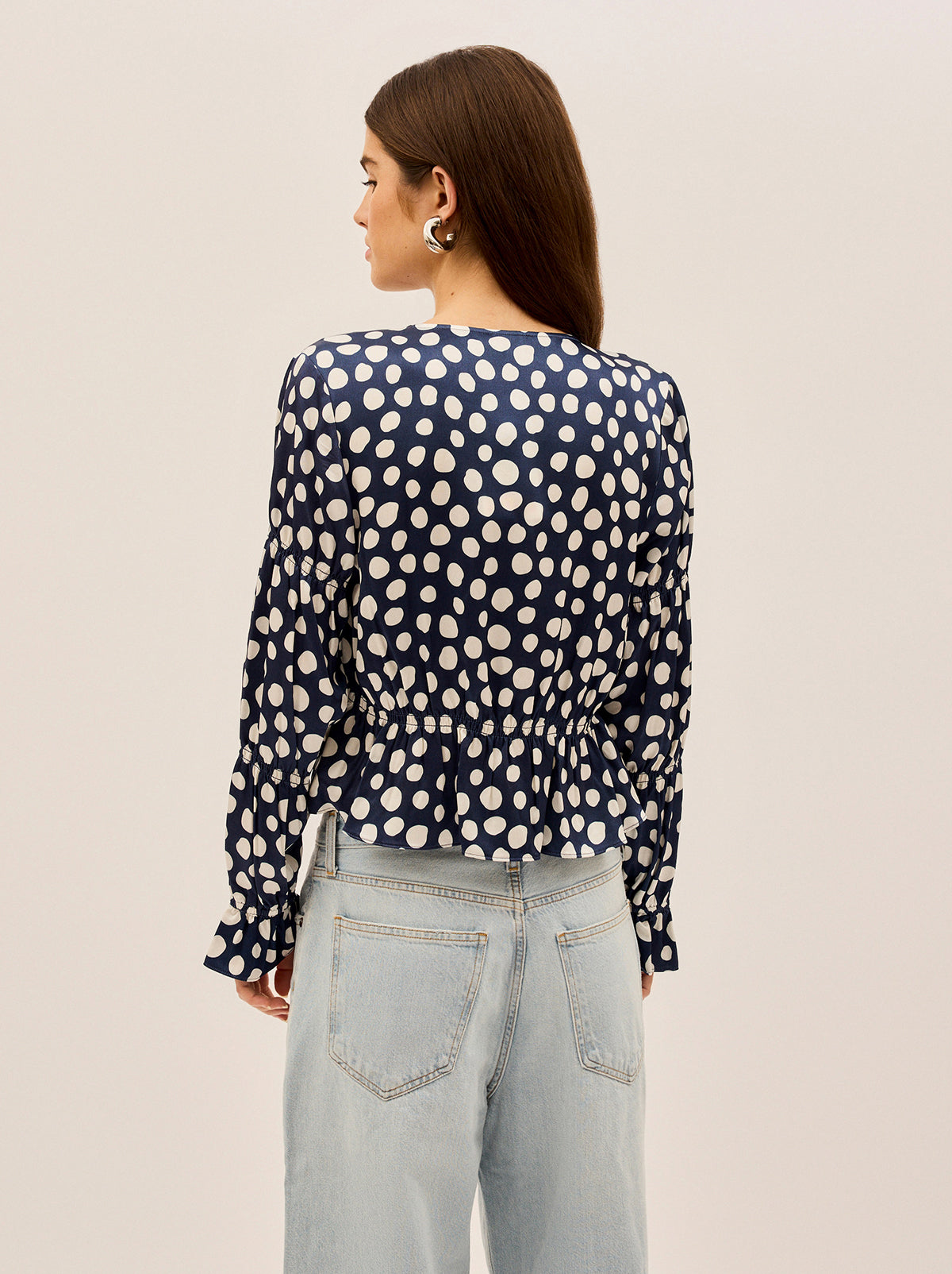 Maia Navy Polka Dot Satin Top by Kitri Studio. Vintage-inspired with a modern edge, the Maia Top is here to elevate your wardrobe.  Designed in luxurious satin with a flattering gathered bodice and sleeves, this long-sleeve blouse brings effortless femininity to any look. V-neck. Long sleeves. Frilled cuffs. 100%% Viscose.