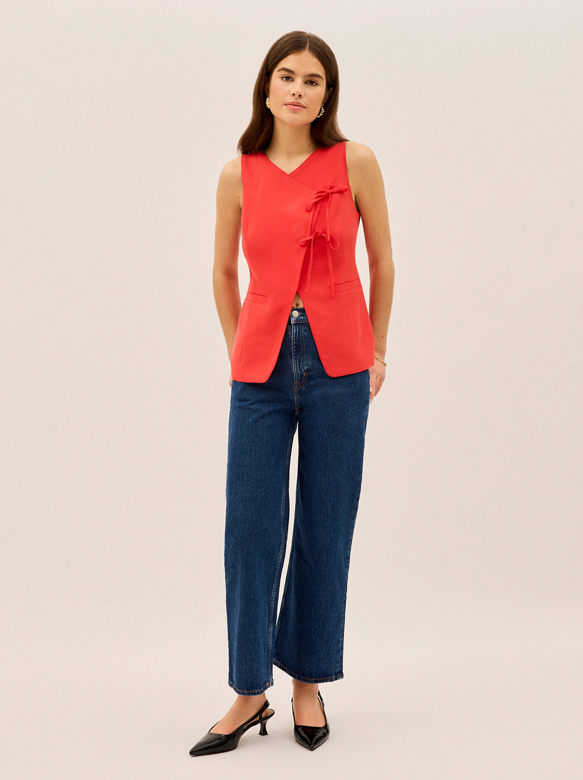 Lea Red Tie Front Waistcoat by Kitri Studio. Step into effortless sophistication with our Lea waistcoat - a contemporary take on classic tailoring that adds instant polish to any look.  This vibrant red piece features a thoughtfully designed signature tie detail at the front that creates a flattering and elegant asymmetric finish while adding a touch of playful twist. V-neck. Sleeveless. Front ties. SHELL: Lenzing TM 70%% Tencel 30%% Linen Lining: 100%% Recycled Polyester.