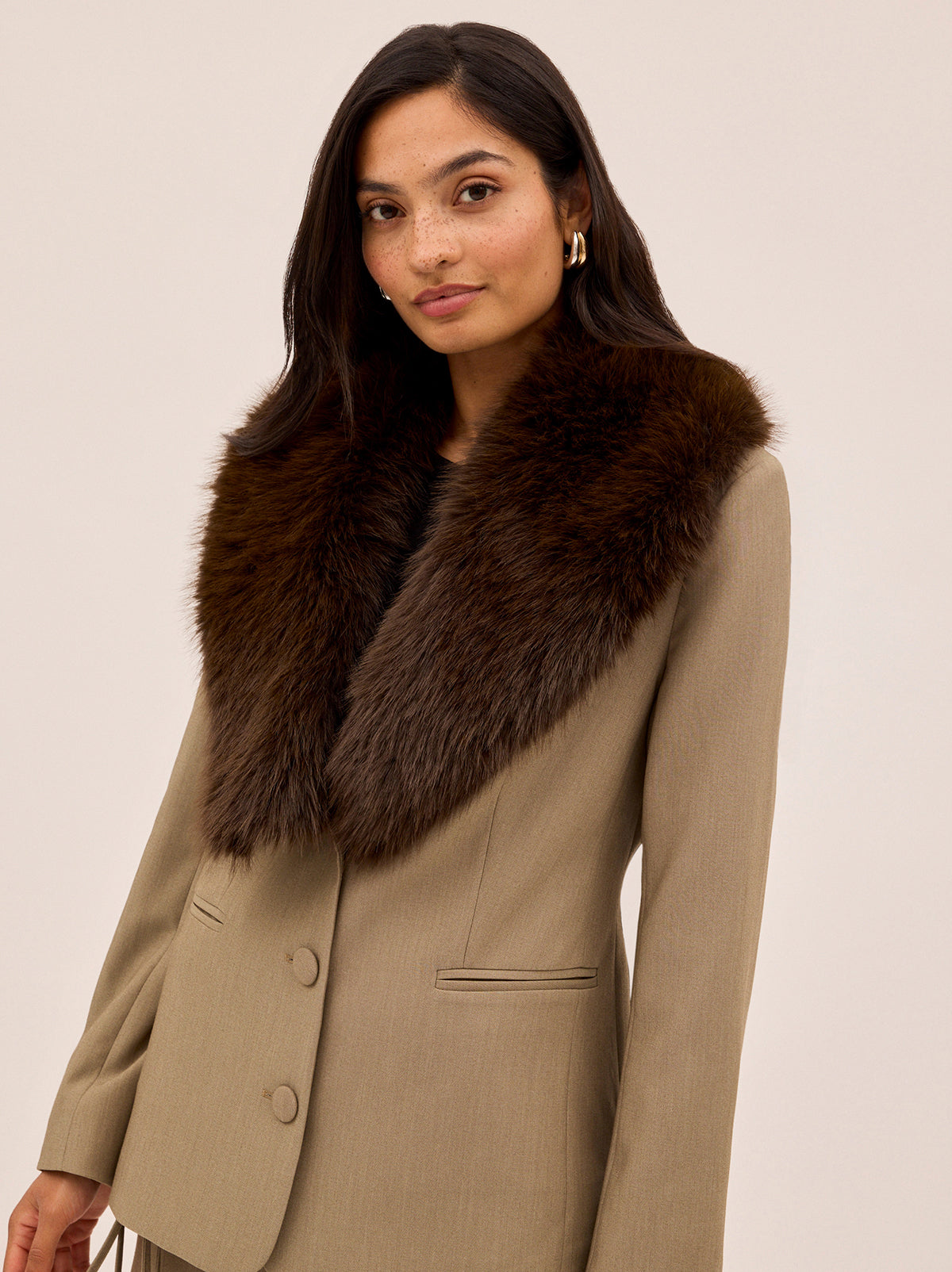 Anthia Tailored Blazer by Kitri Studio. The Anthia blazer brings statement-making polish to your wardrobe.  Expertly tailored in a versatile taupe hue, it’s cinched at the waist for a flattering fit and finished with a detachable faux-fur collar in rich chocolate brown for a touch of vintage glamour. Long sleeves. Button front. Fully lined. Main: 74% Polyester, 20% Rayon, 6% Elastane Faux Fur: 100% Polyester.