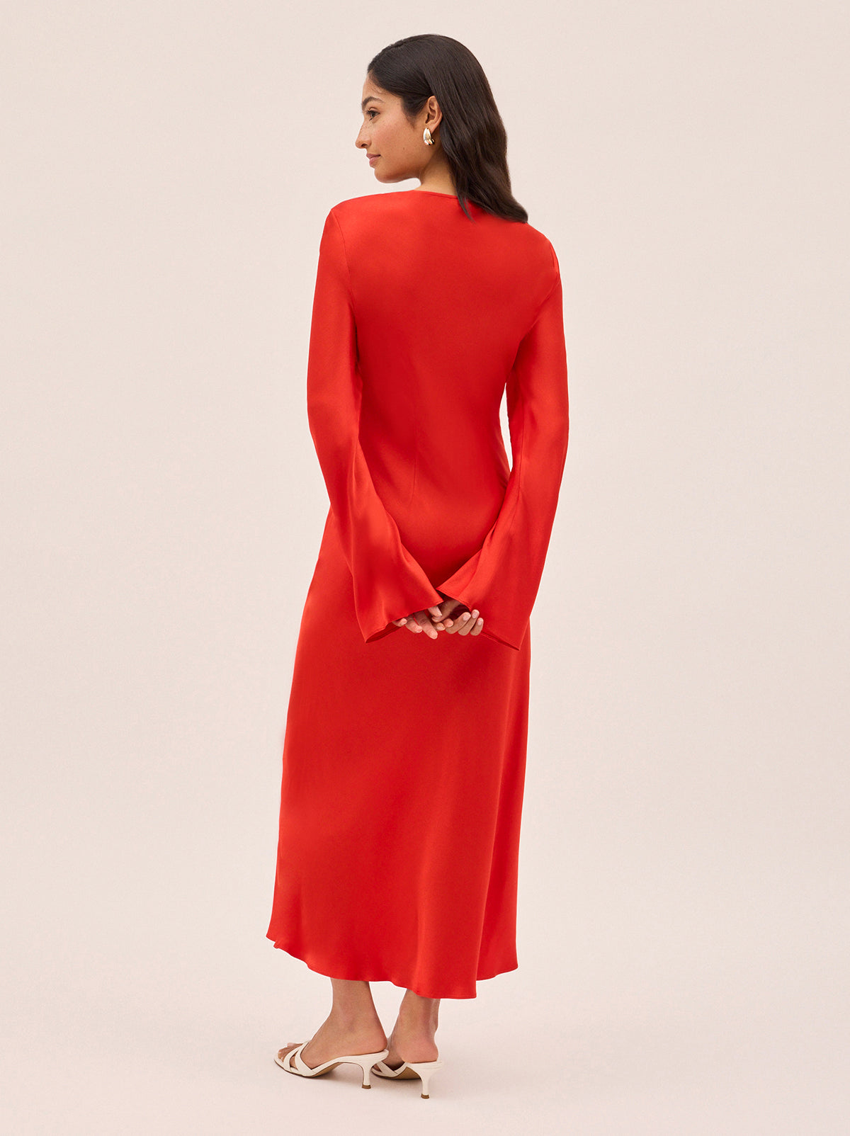 Camille Red Satin Dress by Kitri Studio. Cut on the bias for a fluid, body-skimming fit, the Camille dress is crafted from lustrous viscose satin in a vibrant, head-turning red.  The square neckline adds a touch of elegance, while long, flared sleeves add a touch of drama and movement. Square neckline. Flared sleeves. Concealed side-zip. 100% Viscose Satin.
