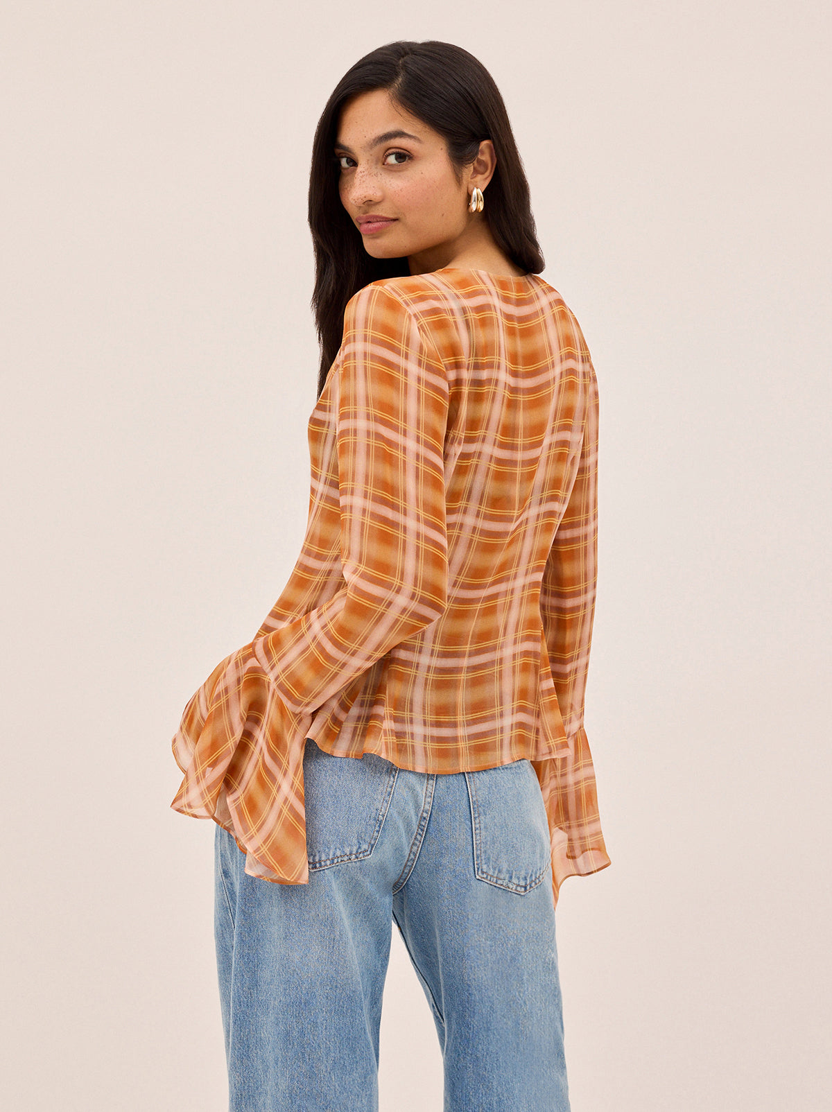 Chantelle Apricot Check Print Top by Kitri Studio. The Chantelle top blends bohemian charm with cool check print.  Crafted from semi-sheer viscose georgette in our in-house designed apricot check, it features flared sleeves, a wide neckline with delicate tie detail, and self-covered buttons through the front. Round neck. Flared sleeves. Button front. 100% Viscose Georgette.