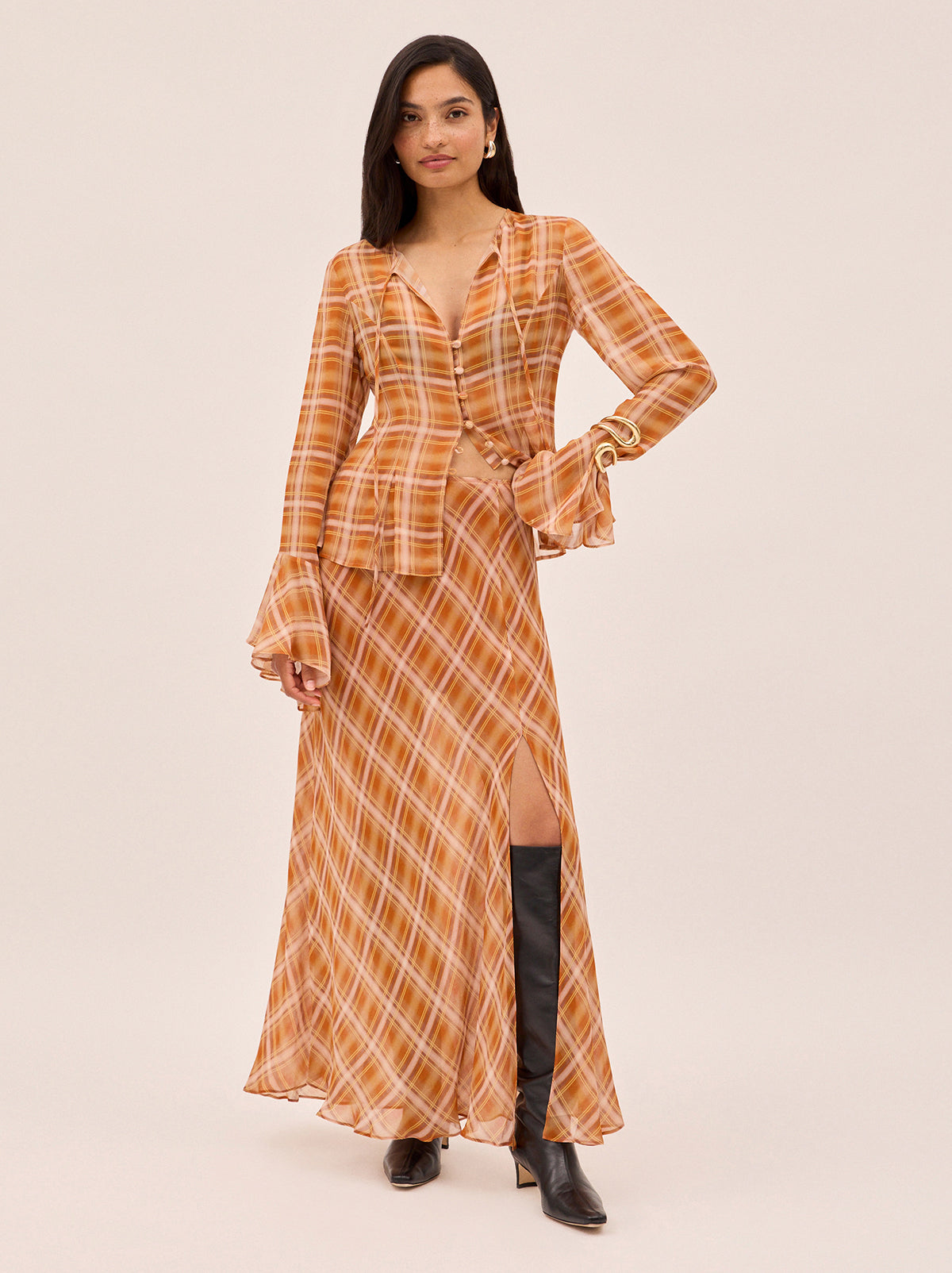 Chantelle Apricot Check Print Top by Kitri Studio. The Chantelle top blends bohemian charm with cool check print.  Crafted from semi-sheer viscose georgette in our in-house designed apricot check, it features flared sleeves, a wide neckline with delicate tie detail, and self-covered buttons through the front. Round neck. Flared sleeves. Button front. 100% Viscose Georgette.