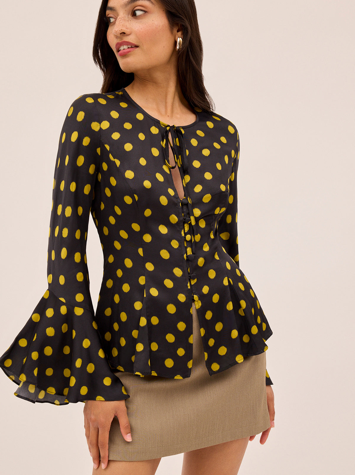 Chantelle Black Polka Dot Satin Top by Kitri Studio. The Chantelle top blends bohemian charm with modern polish in classic-with-a-twist chartreuse polka dot  print.  Crafted from lustrous and fluid viscose satin, it features flared sleeves, a wide neckline with delicate tie detail, and self-covered buttons through the front. Round neck. Flared sleeves. Button front. 100% Viscose.
