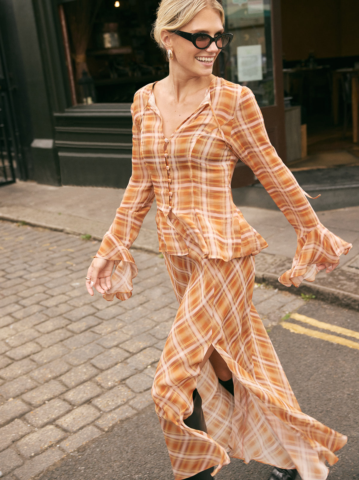 Zoe Apricot Check Print Skirt by Kitri Studio. The Zoe skirt is a flowing, feminine maxi crafted from semi-sheer viscose georgette in our exclusive apricot check print.  Designed with a mid-rise fit, it features a leg-baring split and is half lined for just the right amount of coverage. Half-lined. Elasticed waist. Flared skirt. 100% Viscose Georgette.