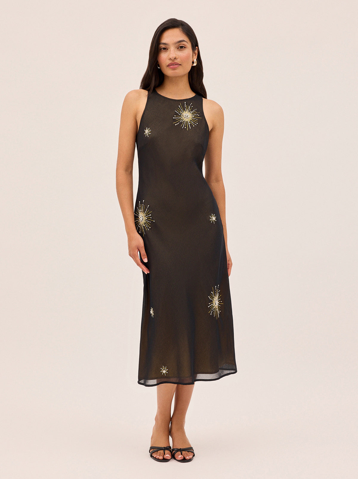 Clarisse Black Embellished Dress by Kitri Studio. The Clarisse Black Embellished Dress is a sophisticated occasion wear piece designed to turn heads.  Crafted from lightweight, semi-sheer viscose georgette, this bias-cut midi dress drapes beautifully over the body for a flattering fit. Round neck. sleeveless. Concealed side-zip. 100% Recycled Polyester.