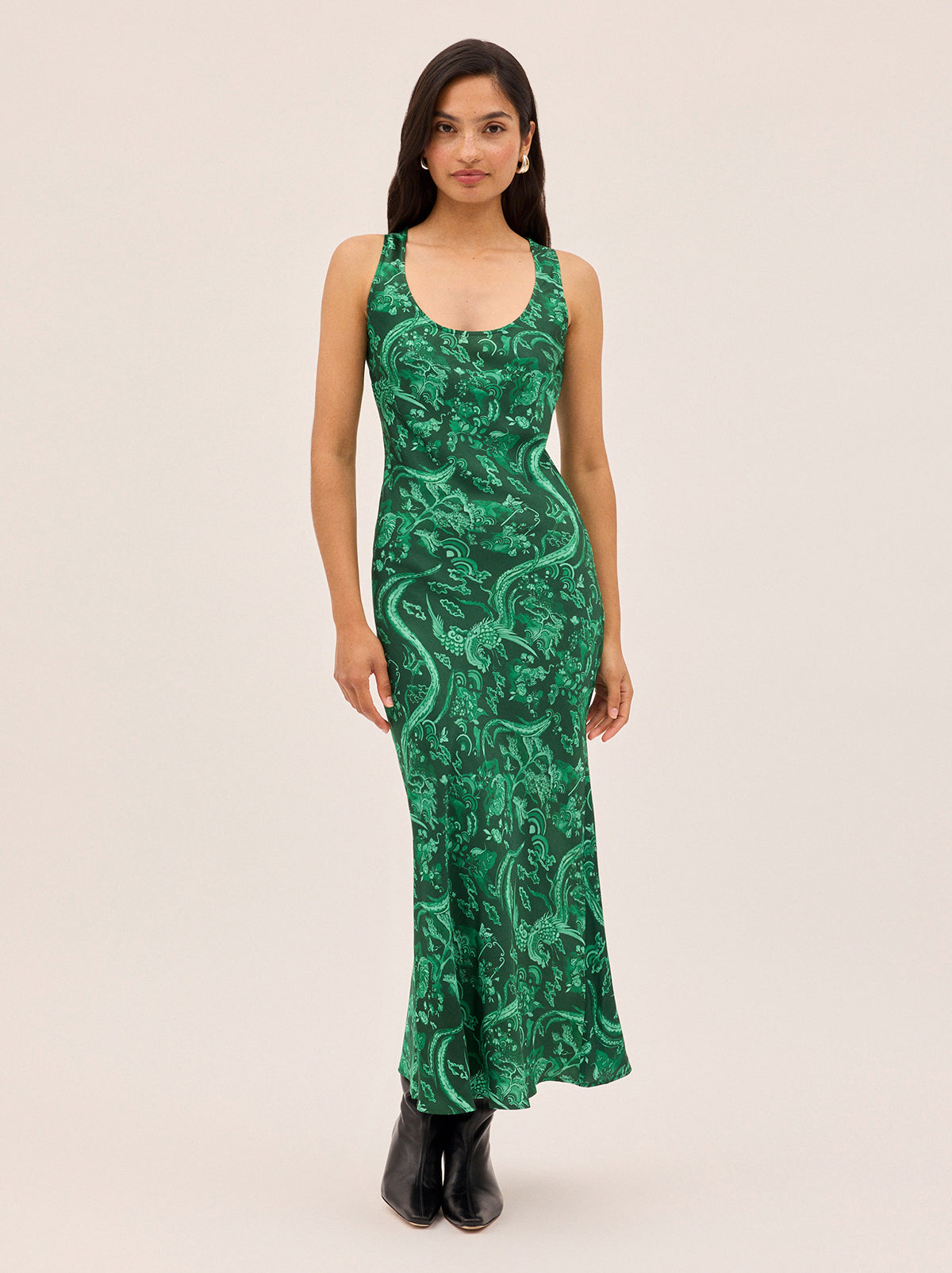 Elise Green Phoenix Print Dress by Kitri Studio. Cut on the bias for a flattering, fluid drape, the Elise Dress showcases our in-house designed Phoenix print in a rich, jewel-toned green.  The minimalist silhouette keeps the focus on the striking motif, while the scoop neckline and clean lines make it an easy, versatile choice for day-to-night dressing. Round neck. sleeveless. Concealed side-zip. 55% Viscose, 45% Rayon.