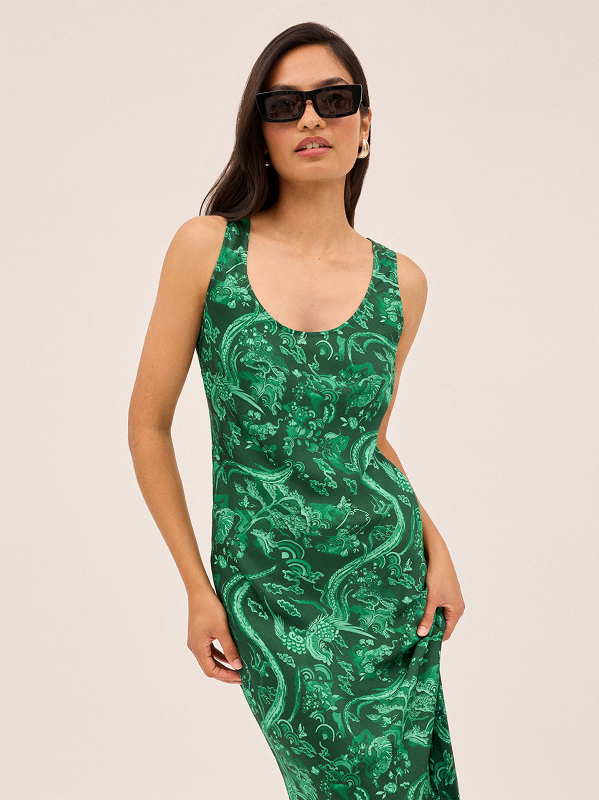 Elise Green Phoenix Print Dress by Kitri Studio. Cut on the bias for a flattering, fluid drape, the Elise Dress showcases our in-house designed Phoenix print in a rich, jewel-toned green.  The minimalist silhouette keeps the focus on the striking motif, while the scoop neckline and clean lines make it an easy, versatile choice for day-to-night dressing. Round neck. sleeveless. Concealed side-zip. 55% Viscose, 45% Rayon.