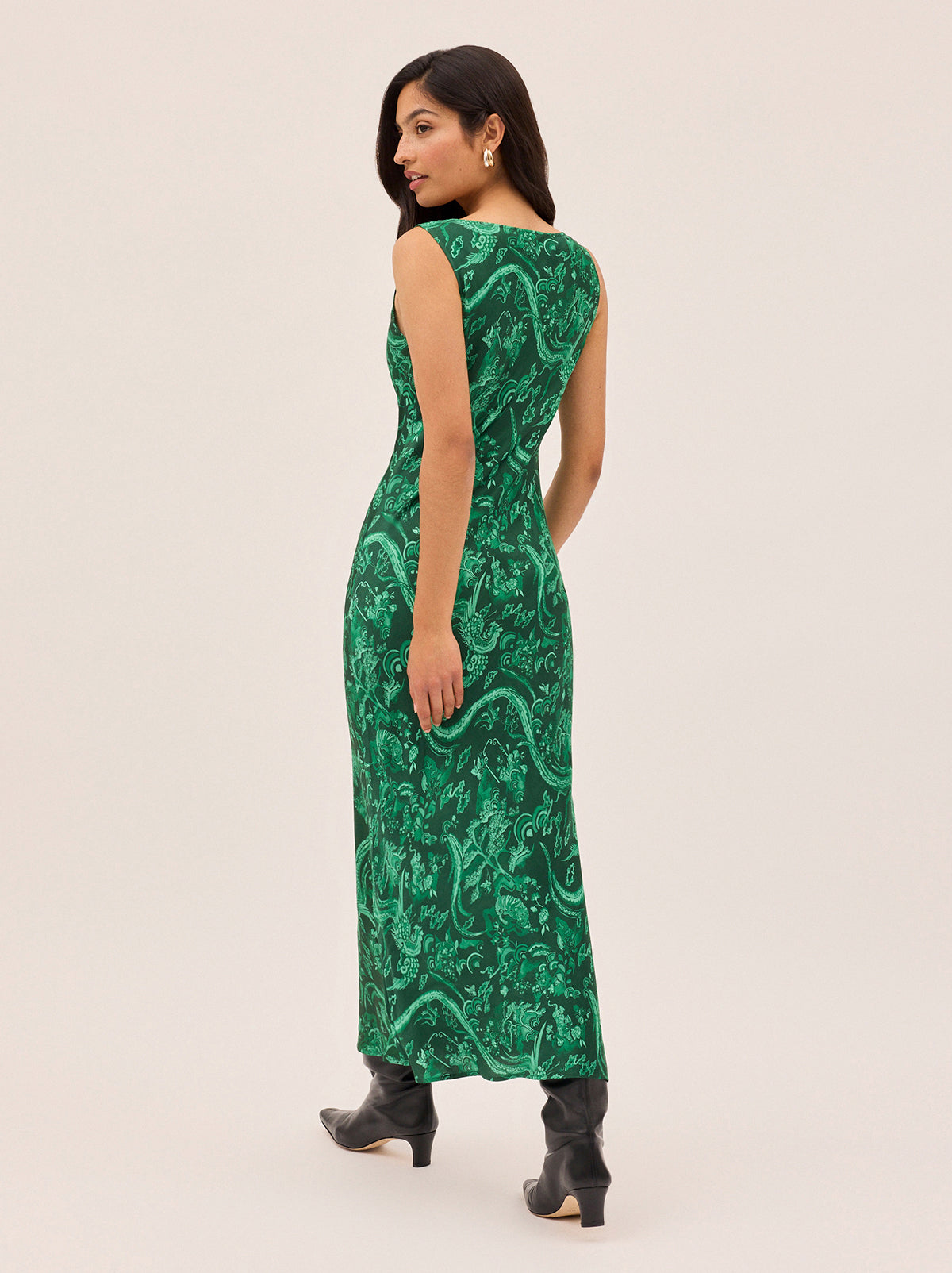 Elise Green Phoenix Print Dress by Kitri Studio. Cut on the bias for a flattering, fluid drape, the Elise Dress showcases our in-house designed Phoenix print in a rich, jewel-toned green.  The minimalist silhouette keeps the focus on the striking motif, while the scoop neckline and clean lines make it an easy, versatile choice for day-to-night dressing. Round neck. sleeveless. Concealed side-zip. 55% Viscose, 45% Rayon.