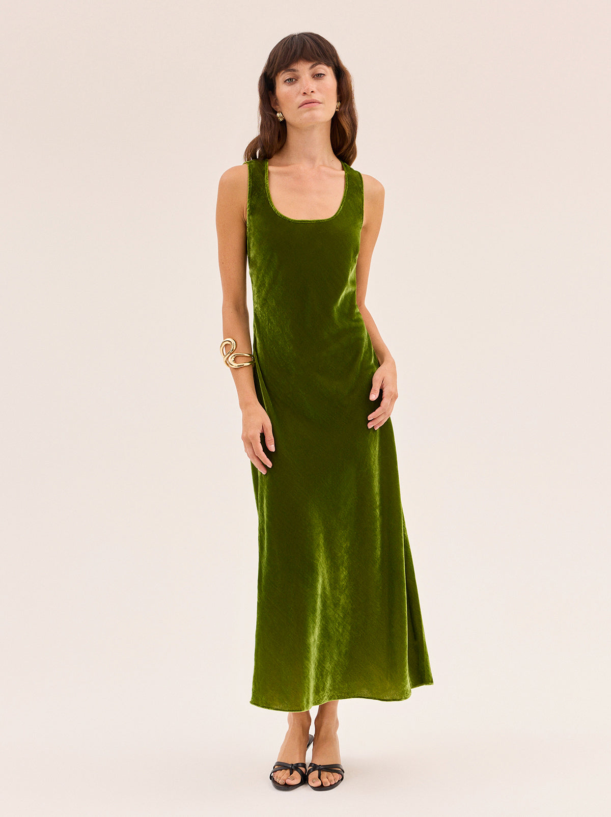 Elise Olive Velvet Dress by Kitri Studio. Cut on the bias for a flattering, fluid drape, the Elise in olive green viscose velvet is '90s-inspired dream dress.  The minimalist silhouette with the scoop neckline and clean lines make it an easy, versatile choice for day-to-night dressing. Scoop neck. Sleeveless. Concealed side-zip. 80% Viscose, 20% Nylon.