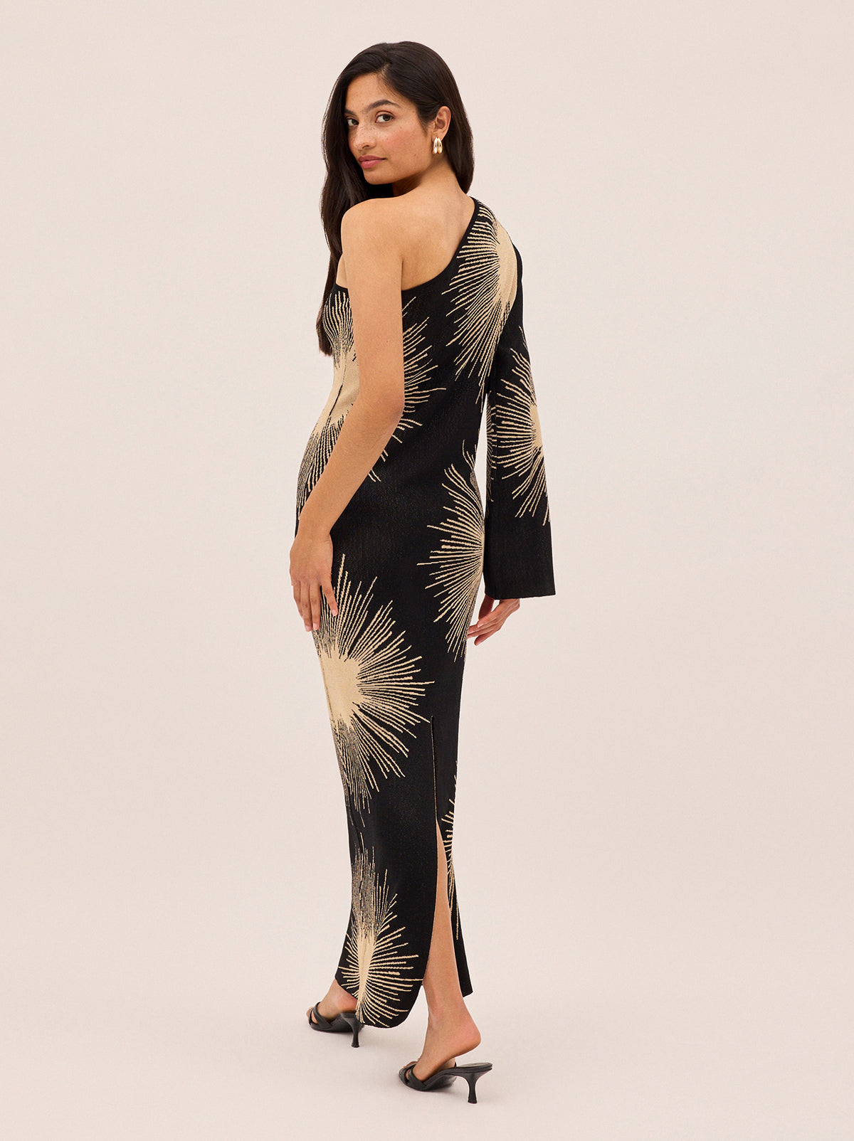 Esme Sunburst Lurex One Shoulder Dress by Kitri Studio. Esme Sunburst Lurex One Shoulder Dress offers a striking silhouette in lightweight lurex knit, perfect for year-round partywear.  Featuring a shimmering sunburst motif jacquard, the design is cut with an asymmetric one-shoulder neckline for a modern, elongating effect. One shoulder. Flared sleeves. A-line skirt. 100% Viscose.