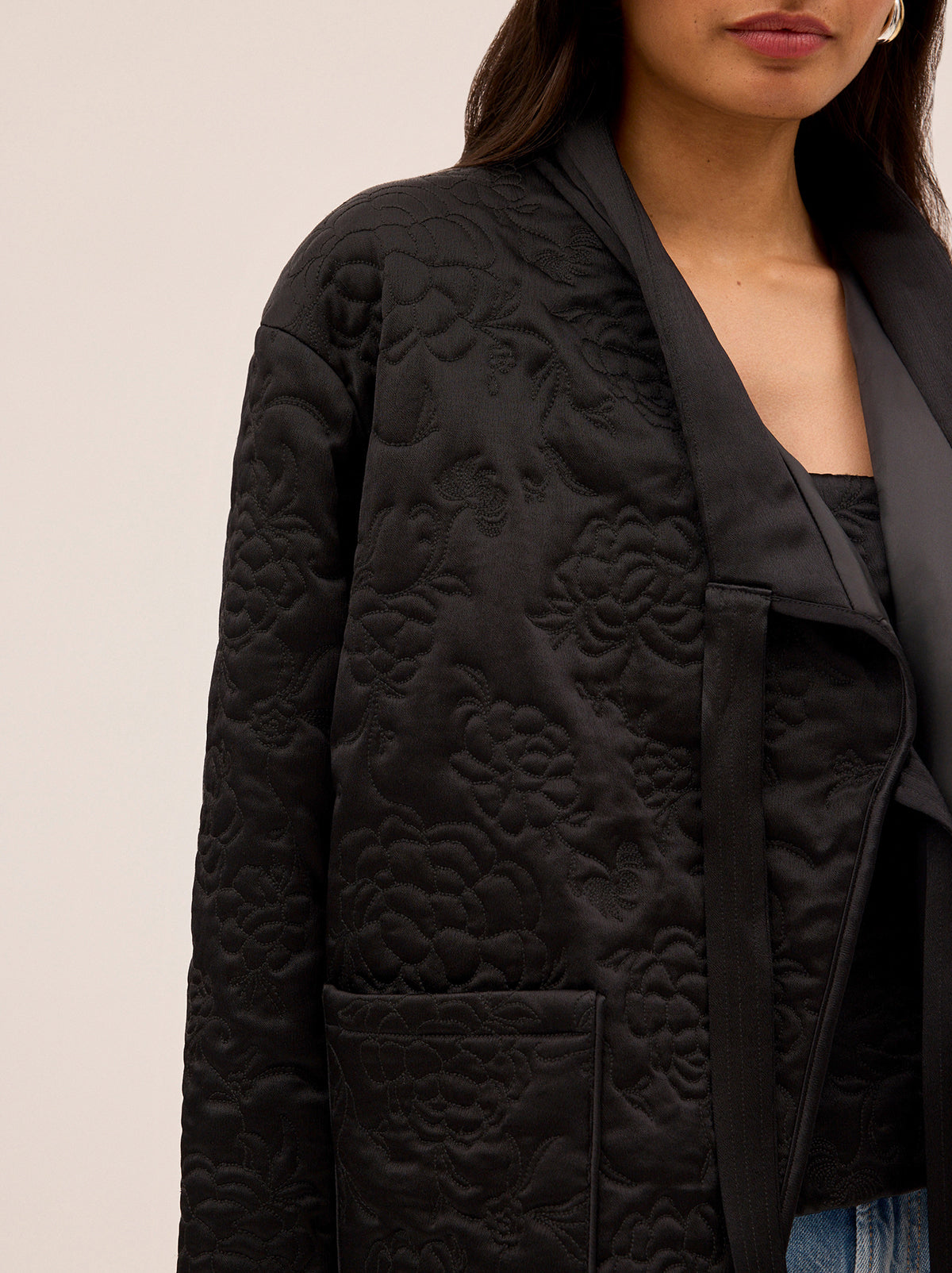 Hani Black Quilted Satin Jacket by Kitri Studio. Lightweight, versatile, and artfully detailed - the Hani jacket is designed to be worn year-round.  Cut from lustrous black viscose satin, it’s lightly quilted with an intricate floral pattern inspired by traditional Korean paintings. V-neck. Long sleeves. Front ties. 97% Viscose, 3% Elastane.
