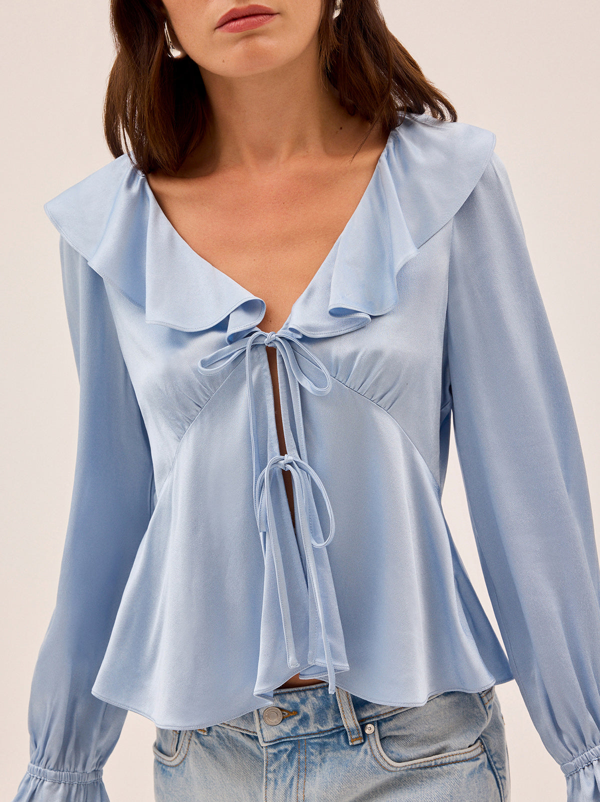 Ione Powder Blue Satin Top by Kitri Studio. Romantic and effortless, the Ione top is new silhouette in soft, fluid viscose satin.  Designed in a dreamy powder blue, it features a deep V-neckline with delicate frill trim, a tie-front fastening, and long sleeves finished with softly gathered cuffs. V-neck. Flared sleeves. Elasticated cuffs. 100% Viscose Satin.