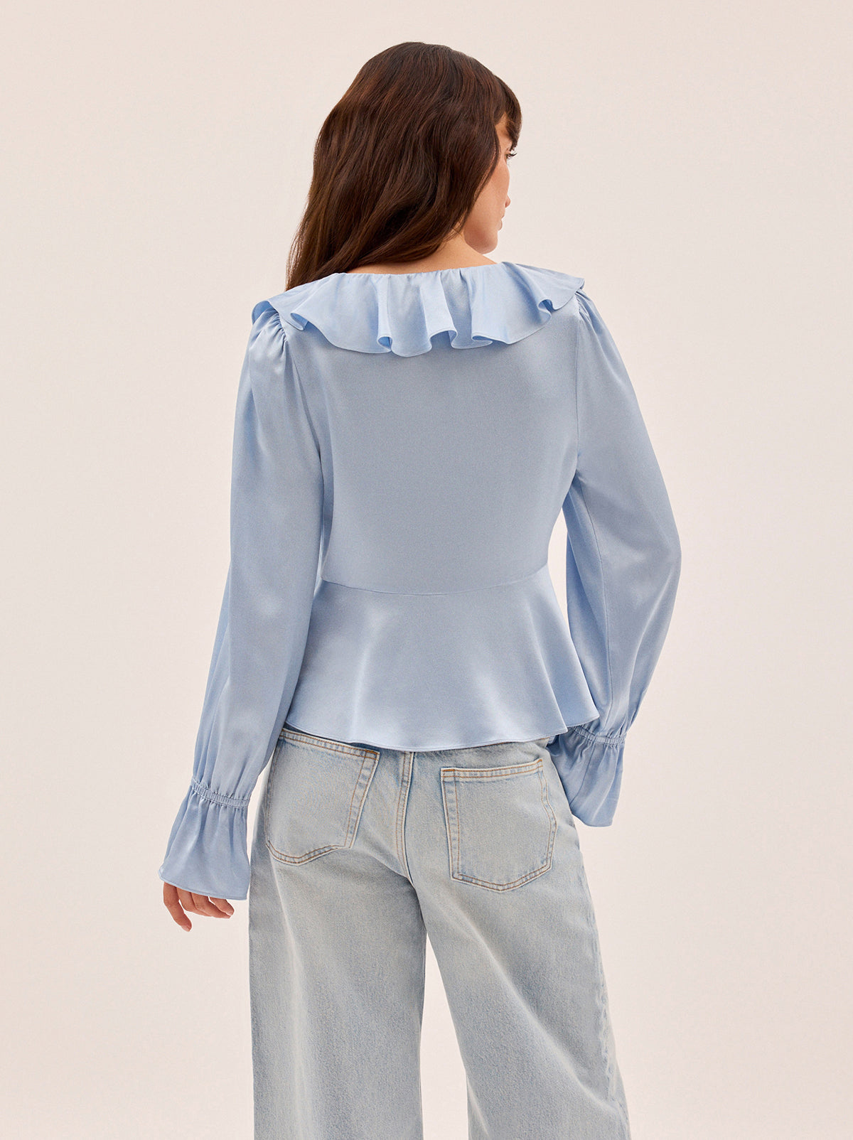 Ione Powder Blue Satin Top by Kitri Studio. Romantic and effortless, the Ione top is new silhouette in soft, fluid viscose satin.  Designed in a dreamy powder blue, it features a deep V-neckline with delicate frill trim, a tie-front fastening, and long sleeves finished with softly gathered cuffs. V-neck. Flared sleeves. Elasticated cuffs. 100% Viscose Satin.