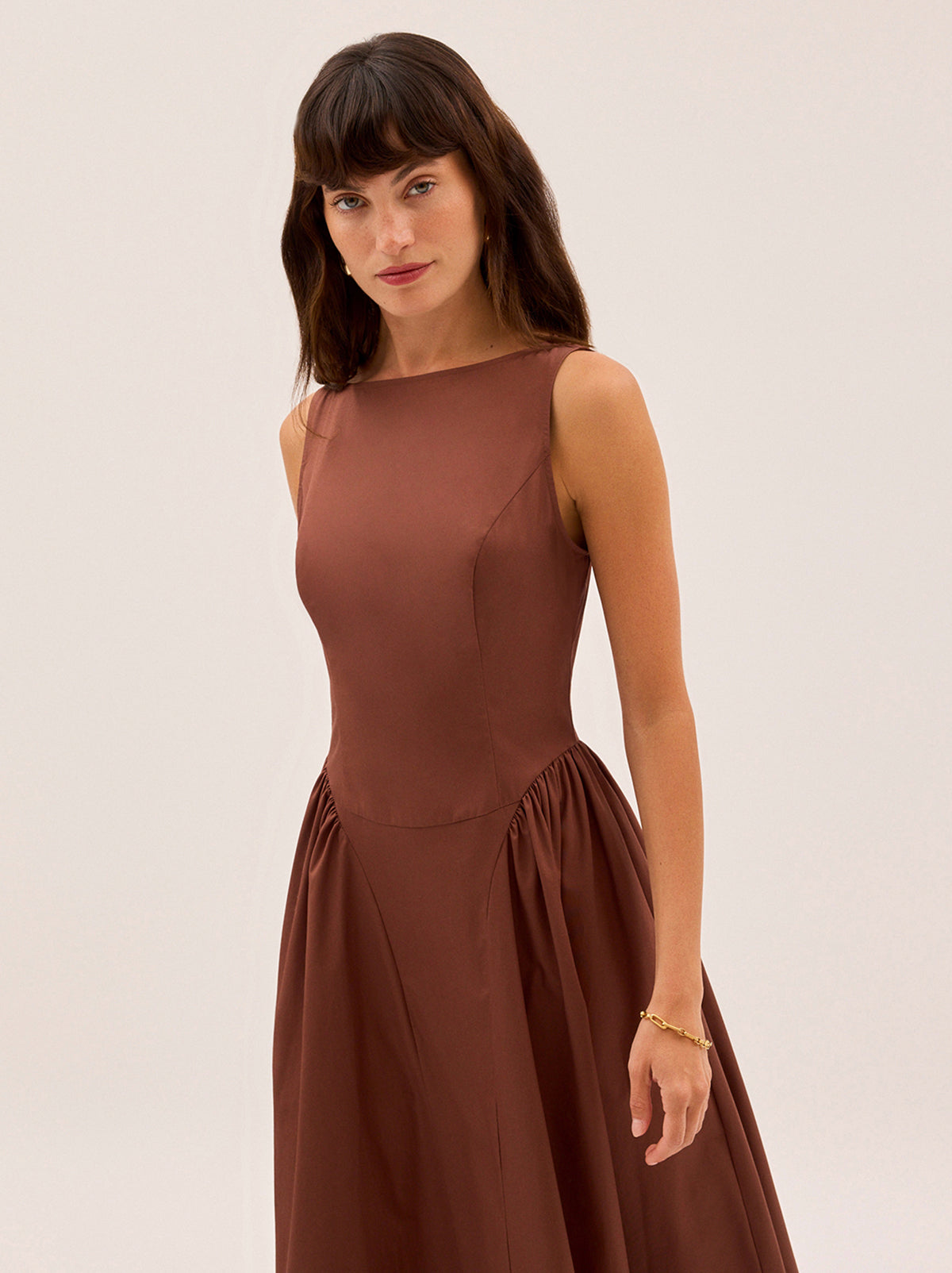 Josephine Sienna Cotton Dress by Kitri Studio. Elegant and effortless, the Josephine dress is crafted from crisp cotton in a warm sienna hue.  Featuring a flattering boat neckline and sleeveless silhouette, it’s designed with softly gathered side panels and a voluminous A-line skirt for graceful movement. Wider crew neck. Sleeveless. Centre-back zip closure. 100% Cotton.