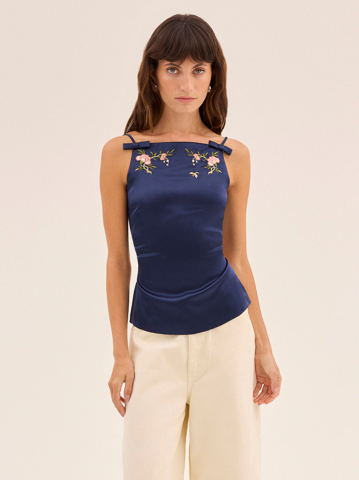 Josie Navy Satin Embroidered Top by Kitri Studio. The Josie top is crafted from timeless navy stretch viscose satin fabrication that feels as good as it looks.  Designed with a high square neckline and feminine bows and delicate floral embroidery details, it features a striking open back with adjustable ties that can be styled multiple ways. Straight neckline. Tie straps. Back ties. 97% Viscose, 3% Elastane Satin .