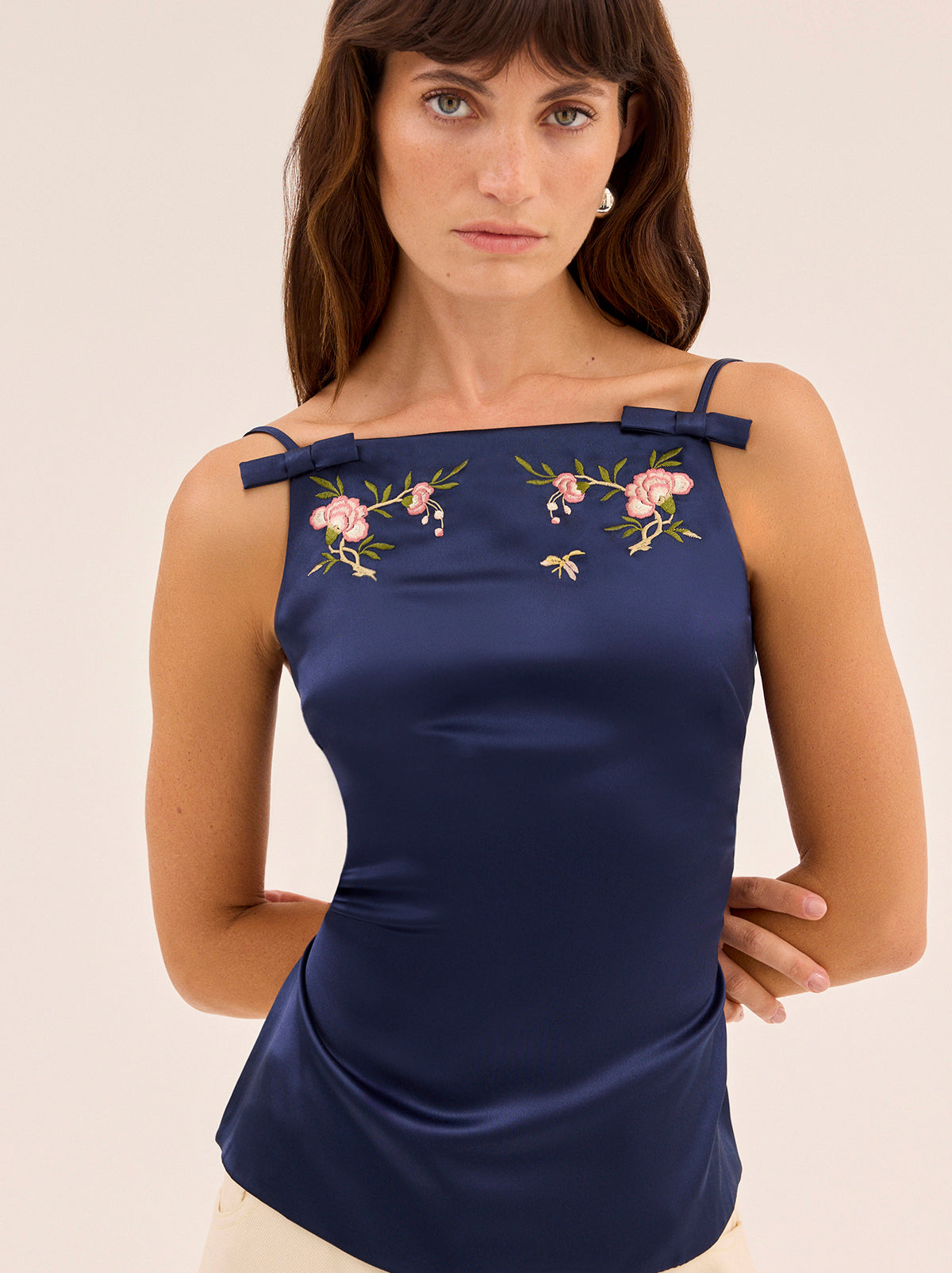 Josie Navy Satin Embroidered Top by Kitri Studio. The Josie top is crafted from timeless navy stretch viscose satin fabrication that feels as good as it looks.  Designed with a high square neckline and feminine bows and delicate floral embroidery details, it features a striking open back with adjustable ties that can be styled multiple ways. Straight neckline. Tie straps. Back ties. 97% Viscose, 3% Elastane Satin .