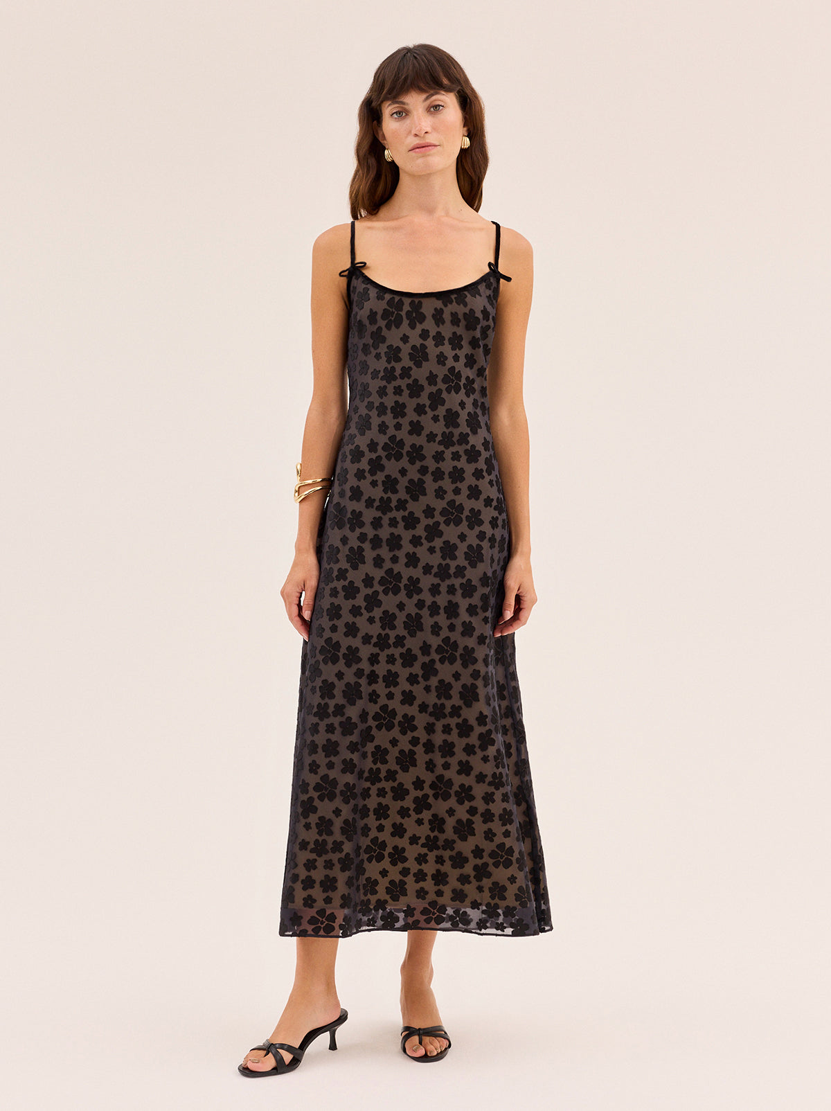 Karla Black Floral Dress by Kitri Studio. Karla Black Floral Dress is cut on the bias from our in-house designed black floral satin burnout, creating a fluid drape that skims the body with ease.  The yellow-gold satin lining adds subtle depth, while black velvet trim and delicate bows frame the neckline for a feminine finish. Scoop neck. Adjustable straps. Fully lined. 75% Viscose, 25% Nylon.