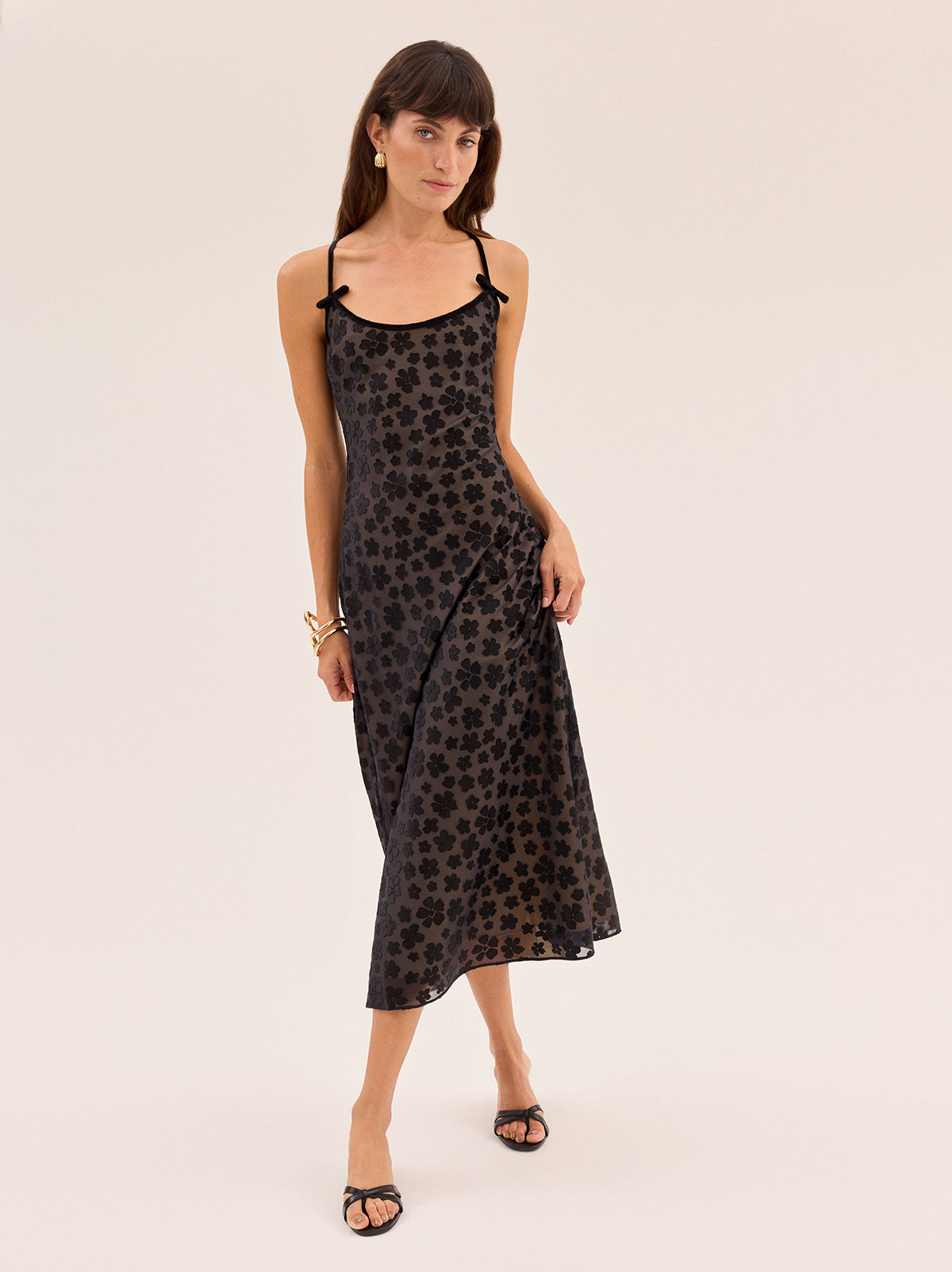 Karla Black Floral Dress by Kitri Studio. Karla Black Floral Dress is cut on the bias from our in-house designed black floral satin burnout, creating a fluid drape that skims the body with ease.  The yellow-gold satin lining adds subtle depth, while black velvet trim and delicate bows frame the neckline for a feminine finish. Scoop neck. Adjustable straps. Fully lined. 75% Viscose, 25% Nylon.