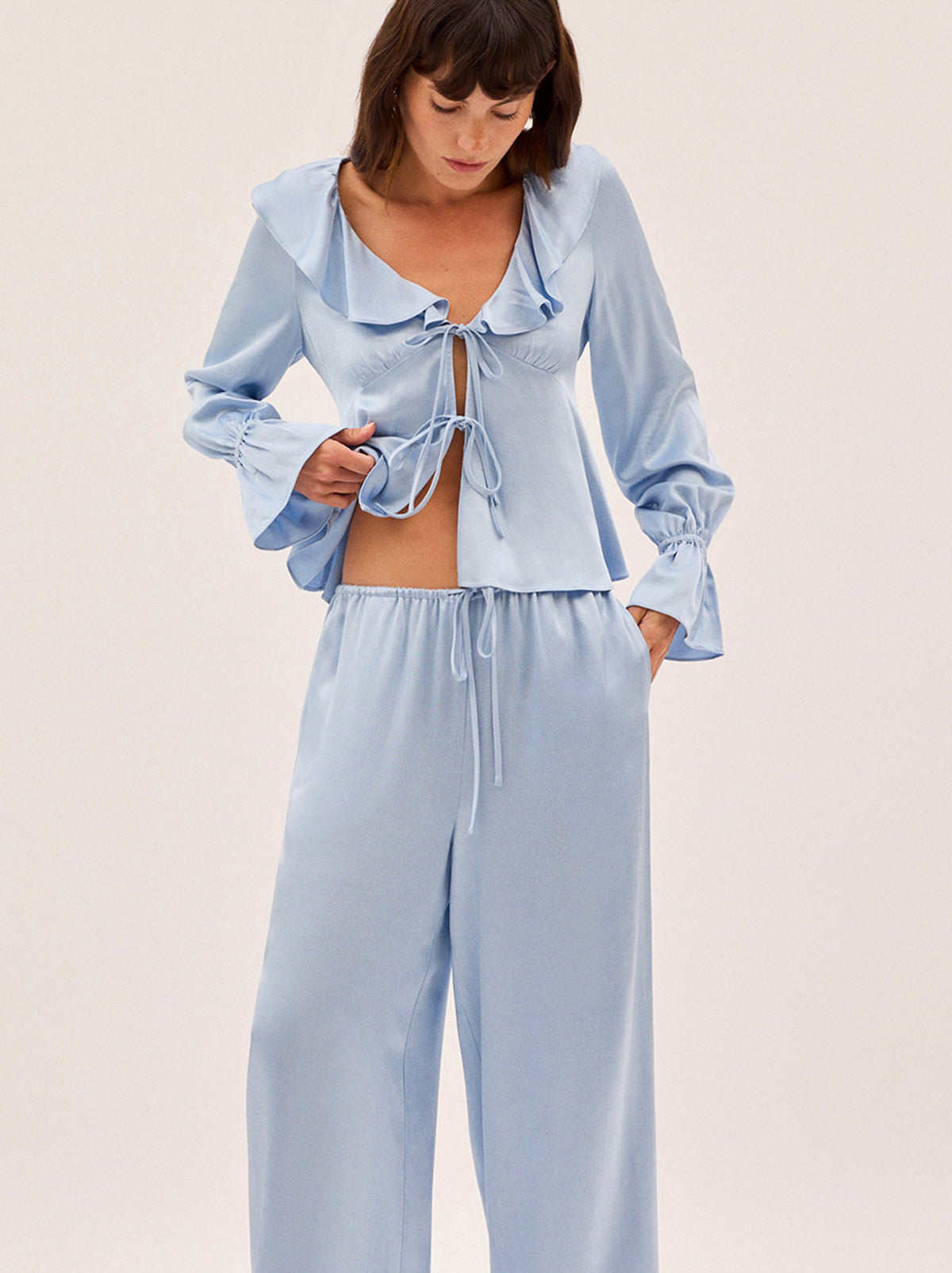 Margaret Powder Blue Satin Trousers by Kitri Studio. Laid-back, but make it luxe.  The Margaret Trousers are crafted from fluid powder blue satin in a relaxed, wide-leg silhouette with a comfortable drawstring waistband. Front ties. Mid Rise. Loose fit. 100% Viscose Satin.