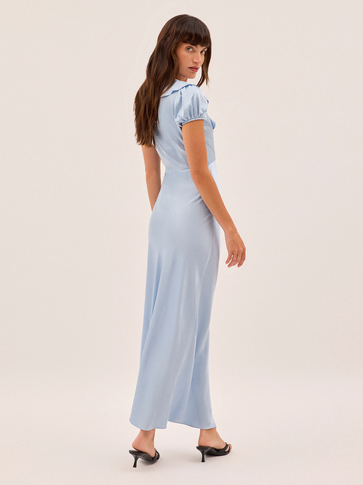 Minka Powder Blue Satin Dress by Kitri Studio. Introducing the Minka dress - a new romantic silhouette in a dreamy powder blue hue.  Crafted from fluid viscose satin and bias-cut for an elegant drape, it features a flattering empire line, deep V-neckline with soft frill detail, and short puff sleeves. V-neck. Puff sleeves. Elasticated cuffs. 100% Viscose Satin.