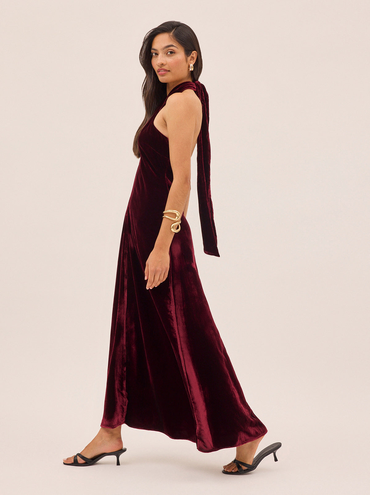 Neve Burgundy Velvet Halter Dress by Kitri Studio. A statement for the season, the Neve Dress is crafted from rich burgundy viscose velvet that drapes beautifully for an effortless yet elevated look.  This bestselling silhouette features a cross-front halterneck that ties elegantly at the back, creating a flattering open-back effect. halter neck. sleeveless. A-line skirt. 80% Viscose, 20% Nylon.
