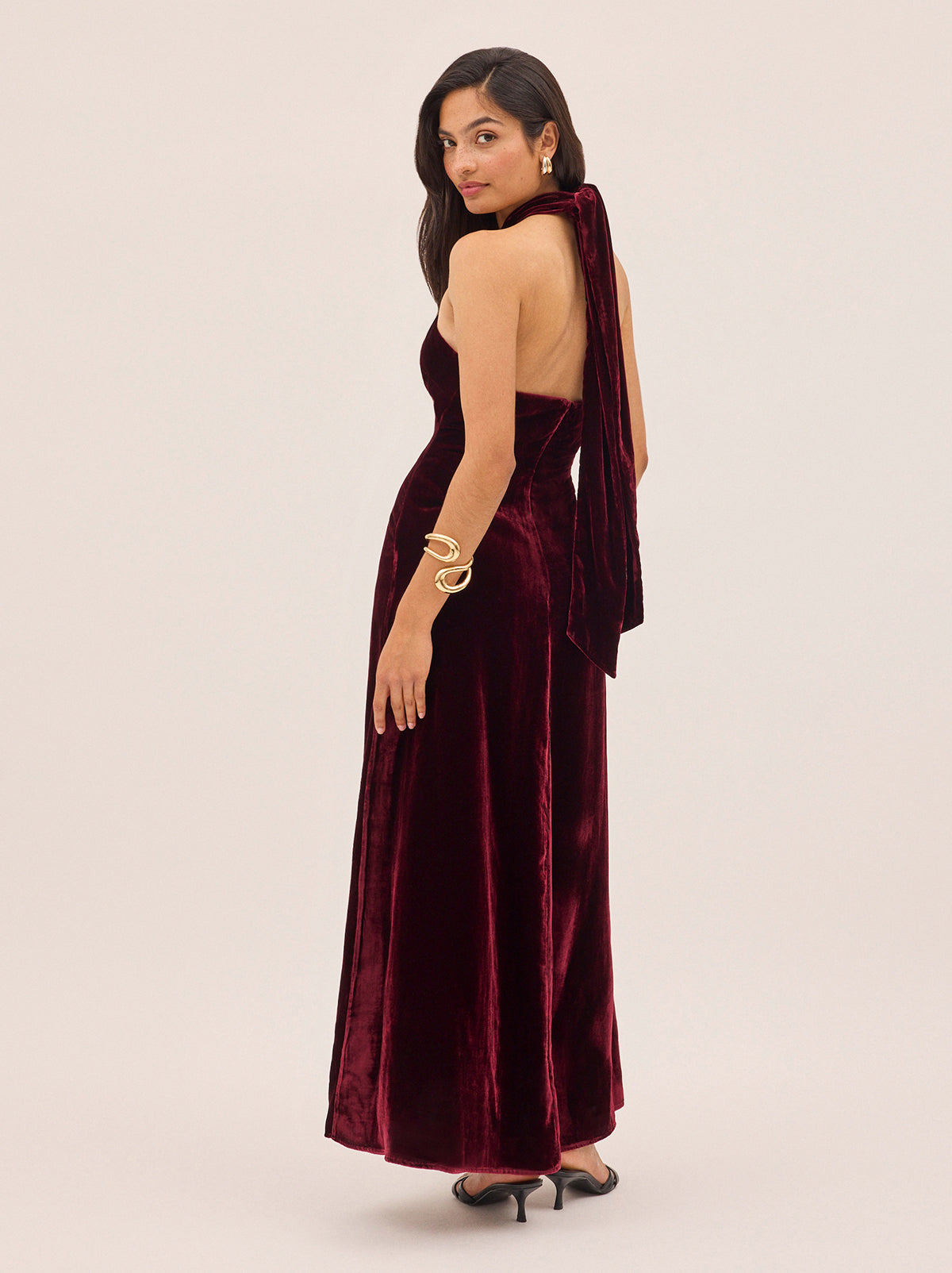 Neve Burgundy Velvet Halter Dress by Kitri Studio. A statement for the season, the Neve Dress is crafted from rich burgundy viscose velvet that drapes beautifully for an effortless yet elevated look.  This bestselling silhouette features a cross-front halterneck that ties elegantly at the back, creating a flattering open-back effect. halter neck. sleeveless. A-line skirt. 80% Viscose, 20% Nylon.