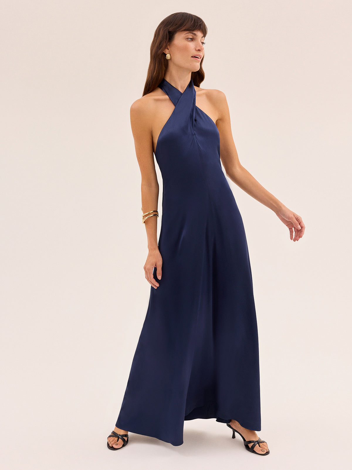 Neve Navy Satin Halterneck Dress by Kitri Studio. Neve Navy Satin Halterneck Dress is designed as a timeless wardrobe investment, combining sophistication with versatility.  Cut from fluid viscose satin, the cross-front halterneck ties at the back for a clean, elegant line, while the bias-cut skirt softly skims the body for a universally flattering fit. Halter neckline. Tie straps. Centre-back zip closure. 97% Viscose, 3% Elastane.