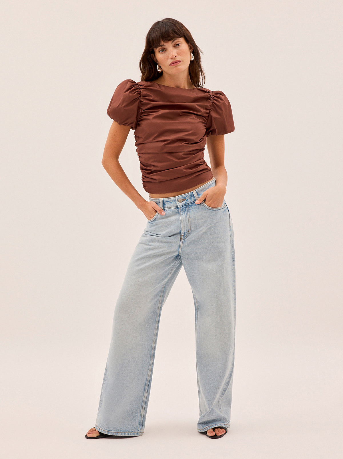 Nyla Sienna Cotton Top by Kitri Studio. The Nyla top is an elevated essential crafted from mid-weight cotton in a rich sienna shade.  Designed with a wide boat neckline and voluminous puffed short sleeves, it features flattering ruching through the body and a slim, sculpted fit. Slash Neck. Puff sleeves. Elasticated cuffs. 100% Cotton.