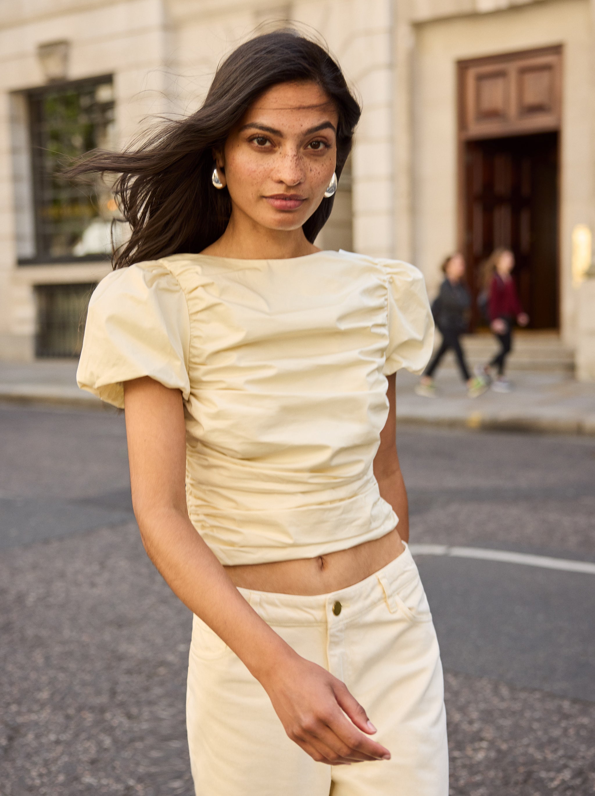 Nyla Vanilla Cotton Top by Kitri Studio. The Nyla top is an elevated essential crafted from mid-weight cotton in a rich vanilla shade.  Designed with a wide boat neckline and voluminous puffed short sleeves, it features flattering ruching through the body and a slim, sculpted fit. Slash Neck. Puff sleeves. Elasticated cuffs. 100% Cotton.