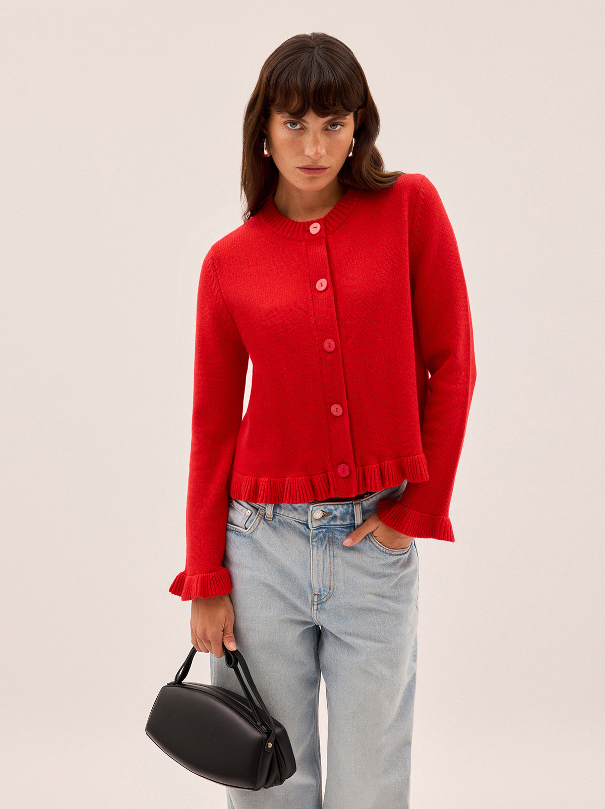 Odile Red Knit Cardigan by Kitri Studio. The Odile cardigan is a refined wardrobe staple with a playful twist.  Knitted from a soft, mid-weight cashmere blend, it features a classic button-down front, with delicate frill detailing at the hem and cuffs. Round neck. Long sleeves. Frilled cuffs. 5% Cashmere, 20% Wool, 27% Viscose, 48% Nylon.