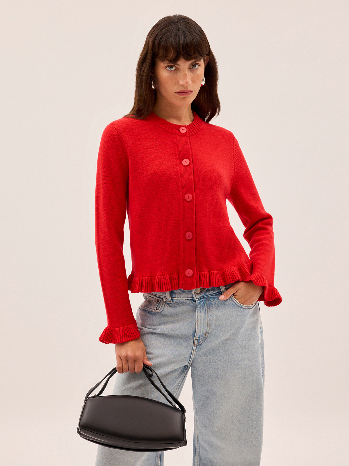 Odile Red Knit Cardigan by Kitri Studio. The Odile cardigan is a refined wardrobe staple with a playful twist.  Knitted from a soft, mid-weight cashmere blend, it features a classic button-down front, with delicate frill detailing at the hem and cuffs. Round neck. Long sleeves. Frilled cuffs. 5% Cashmere, 20% Wool, 27% Viscose, 48% Nylon.