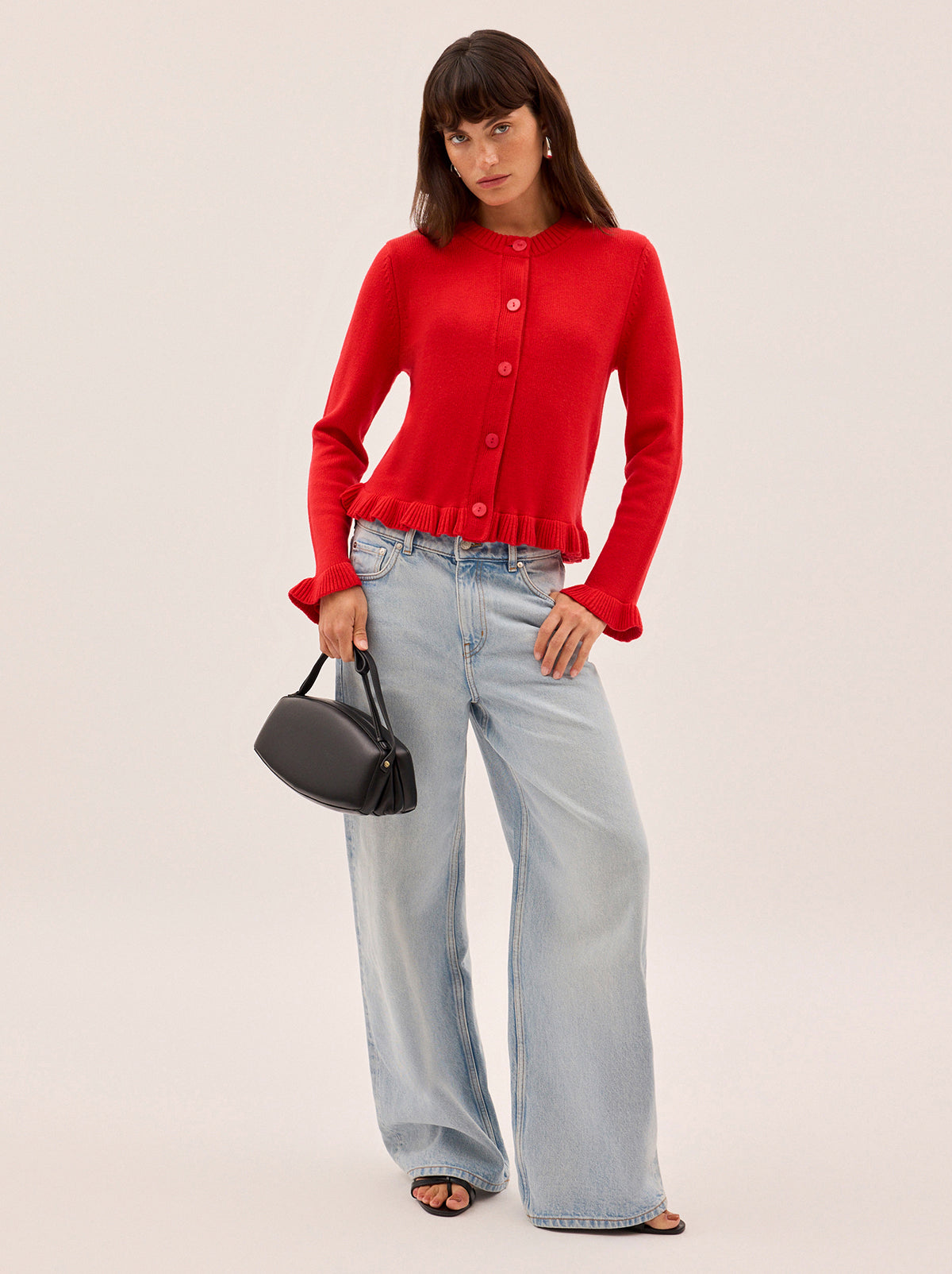 Odile Red Knit Cardigan by Kitri Studio. The Odile cardigan is a refined wardrobe staple with a playful twist.  Knitted from a soft, mid-weight cashmere blend, it features a classic button-down front, with delicate frill detailing at the hem and cuffs. Round neck. Long sleeves. Frilled cuffs. 5% Cashmere, 20% Wool, 27% Viscose, 48% Nylon.