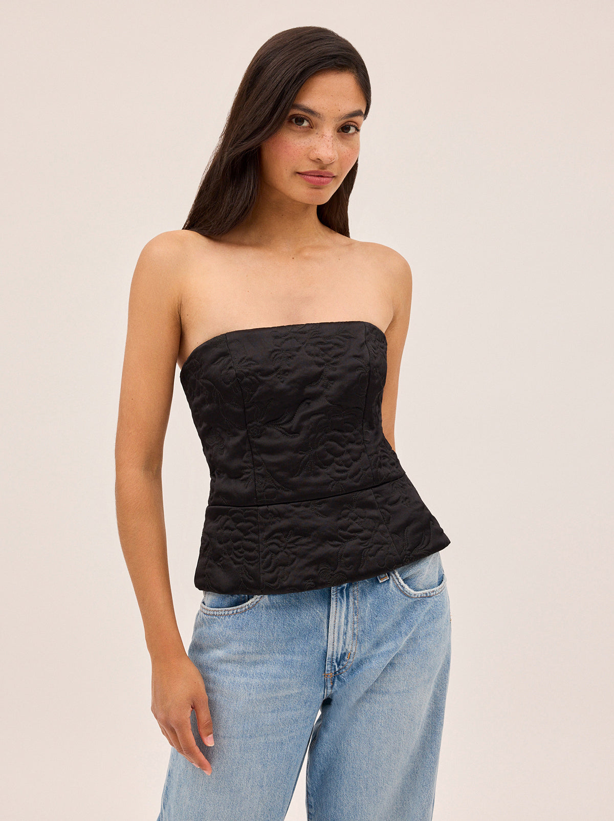 Petra Black Quilted Satin Bandeau Top by Kitri Studio. Perfect for Autumn/Winter, corset-inspired Petra Bandeau top is crafted from lustrous black viscose satin and lightly quilted with a floral motif inspired by traditional Korean paintings.  A peplum hem adds subtle structure, while a centre-back zip and shirred panel ensure a comfortable, flexible fit. Strapless. Concealed side-zip. Fully lined. 97% Viscose, 3% Elastane.