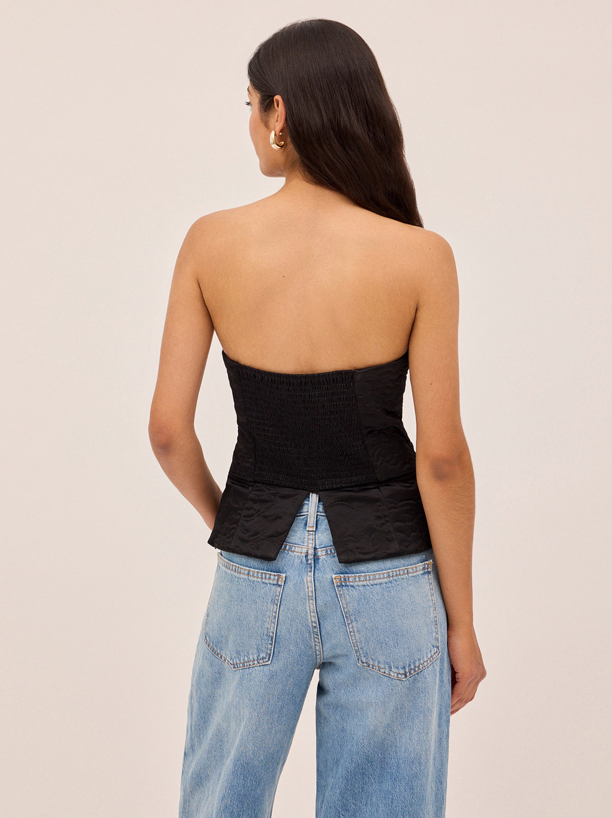 Petra Black Quilted Satin Bandeau Top by Kitri Studio. Perfect for Autumn/Winter, corset-inspired Petra Bandeau top is crafted from lustrous black viscose satin and lightly quilted with a floral motif inspired by traditional Korean paintings.  A peplum hem adds subtle structure, while a centre-back zip and shirred panel ensure a comfortable, flexible fit. Strapless. Concealed side-zip. Fully lined. 97% Viscose, 3% Elastane.