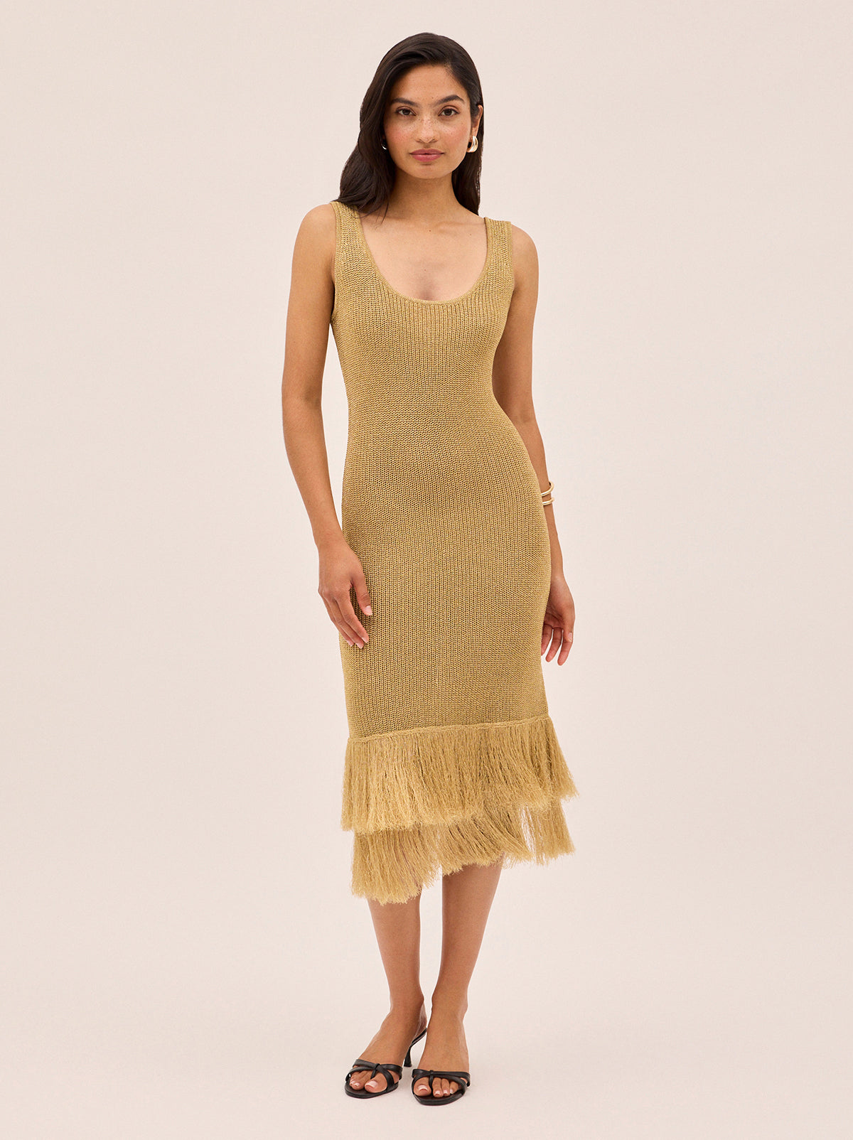 Sandra Gold Lurex Knit Dress by Kitri Studio. Sandra Gold Lurex Knit Dress in a shimmery gold lurex knit offers a body-skimming silhouette that moves effortlessly with you.  Designed with a flattering round neckline, sleeveless cut and double fringe detail at the hem, it radiates a 1920s-inspired charm, perfect for party season or any occasion that calls for a statement piece. Round neck. sleeveless. Length: Midi. 65% Viscose, 35% Lurex.