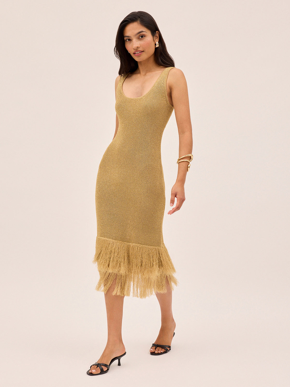 Sandra Gold Lurex Knit Dress by Kitri Studio. Sandra Gold Lurex Knit Dress in a shimmery gold lurex knit offers a body-skimming silhouette that moves effortlessly with you.  Designed with a flattering round neckline, sleeveless cut and double fringe detail at the hem, it radiates a 1920s-inspired charm, perfect for party season or any occasion that calls for a statement piece. Round neck. sleeveless. Length: Midi. 65% Viscose, 35% Lurex.