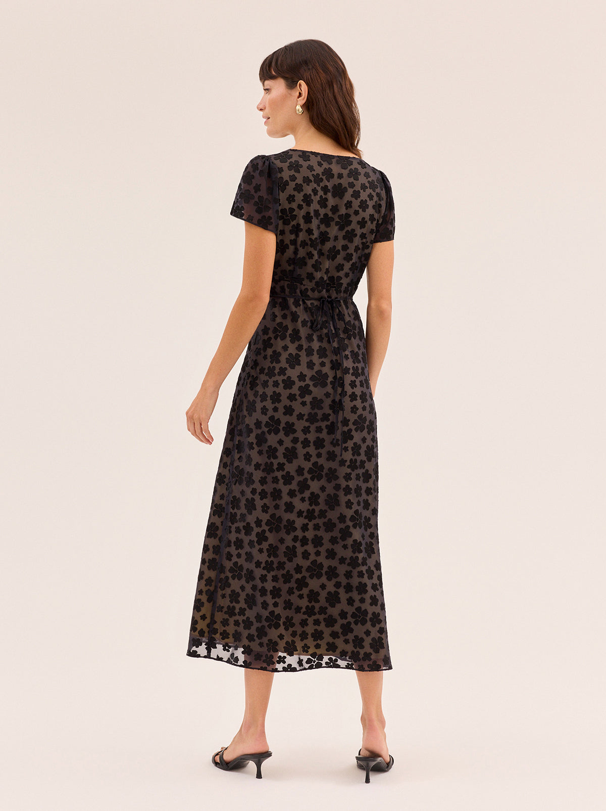 Talia Black Floral Dress by Kitri Studio. Talia Black Floral Dress is a midi-length style crafted from our in-house designed black floral satin burnout.  Bias-cut for a fluid, flattering drape, it’s fully lined in yellow-gold satin that brings subtle warmth and depth to the dark floral design. V-neck. Short sleeves. Concealed side-zip. 75% Viscose, 25% Nylon.