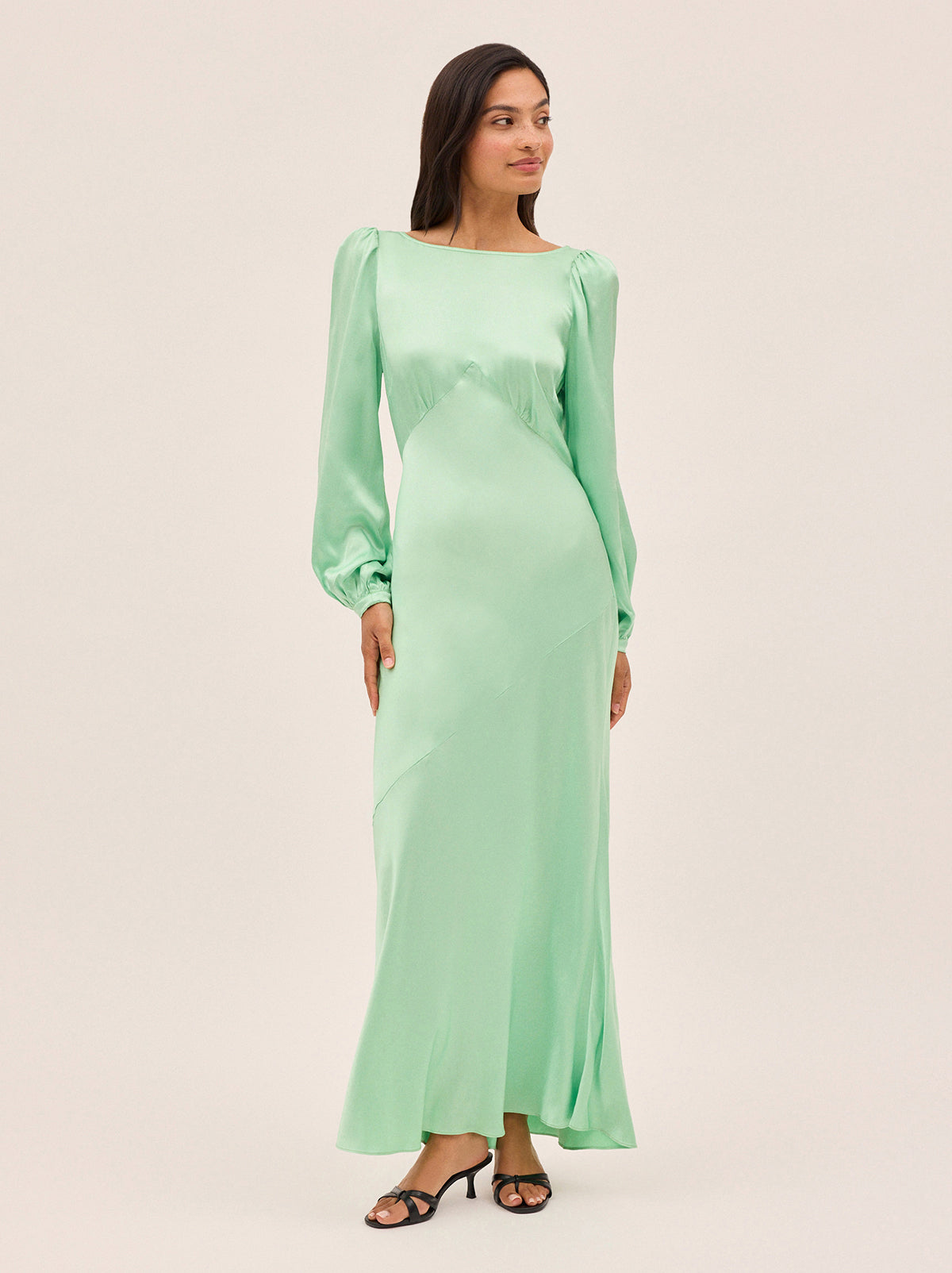 Yara Mint Satin Dress by Kitri Studio. Slip into timeless elegance with this flowing Yara Mint Satin Maxi Dress, designed to turn heads from every angle.  Cut on the bias for a beautifully fluid drape, the skirt features subtle panel detailing and a flattering waist seam that defines your silhouette. Slash Neck. Long sleeves. Bias cut. 100% Viscose Satin.