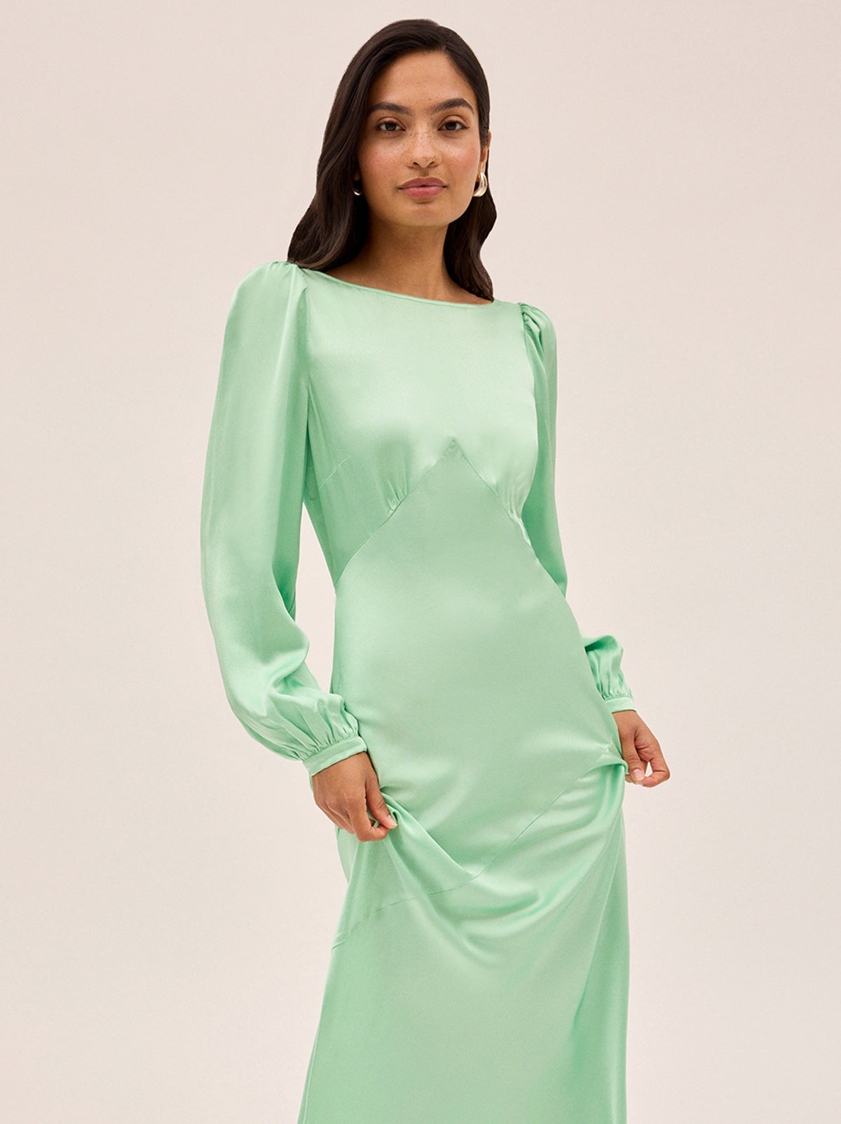 Yara Mint Satin Dress by Kitri Studio. Slip into timeless elegance with this flowing Yara Mint Satin Maxi Dress, designed to turn heads from every angle.  Cut on the bias for a beautifully fluid drape, the skirt features subtle panel detailing and a flattering waist seam that defines your silhouette. Slash Neck. Long sleeves. Bias cut. 100% Viscose Satin.
