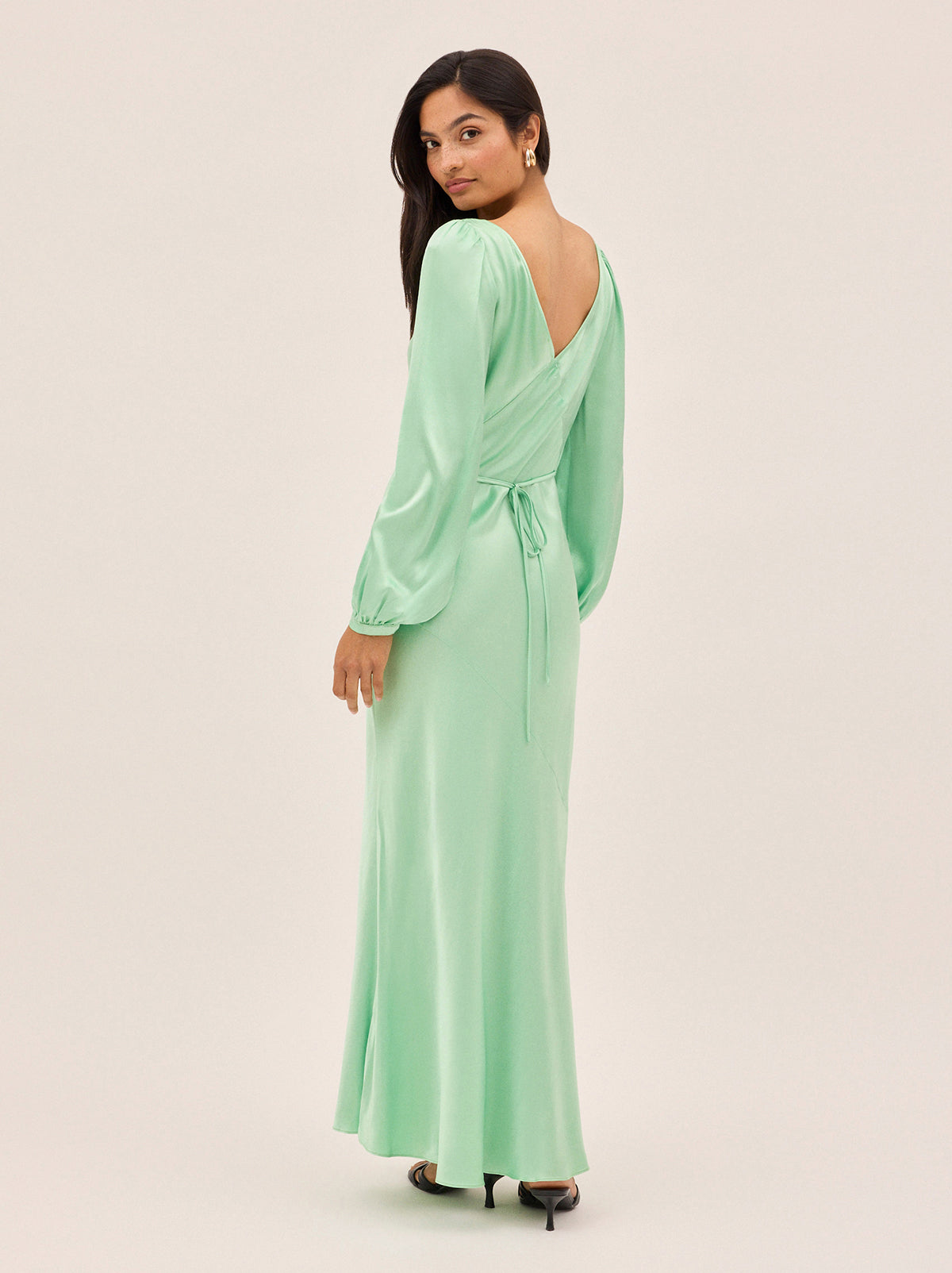 Yara Mint Satin Dress by Kitri Studio. Slip into timeless elegance with this flowing Yara Mint Satin Maxi Dress, designed to turn heads from every angle.  Cut on the bias for a beautifully fluid drape, the skirt features subtle panel detailing and a flattering waist seam that defines your silhouette. Slash Neck. Long sleeves. Bias cut. 100% Viscose Satin.