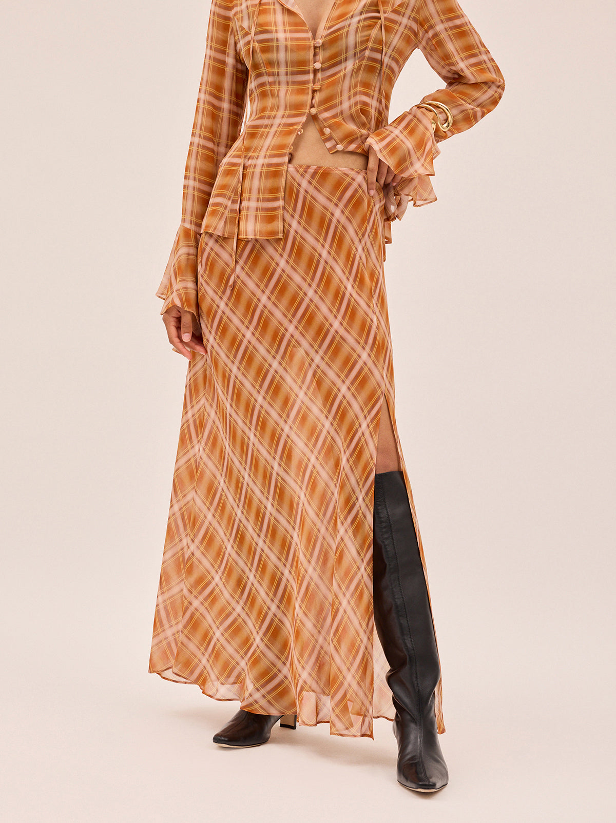 Zoe Apricot Check Print Skirt by Kitri Studio. The Zoe skirt is a flowing, feminine maxi crafted from semi-sheer viscose georgette in our exclusive apricot check print.  Designed with a mid-rise fit, it features a leg-baring split and is half lined for just the right amount of coverage. Half-lined. Elasticed waist. Flared skirt. 100% Viscose Georgette.