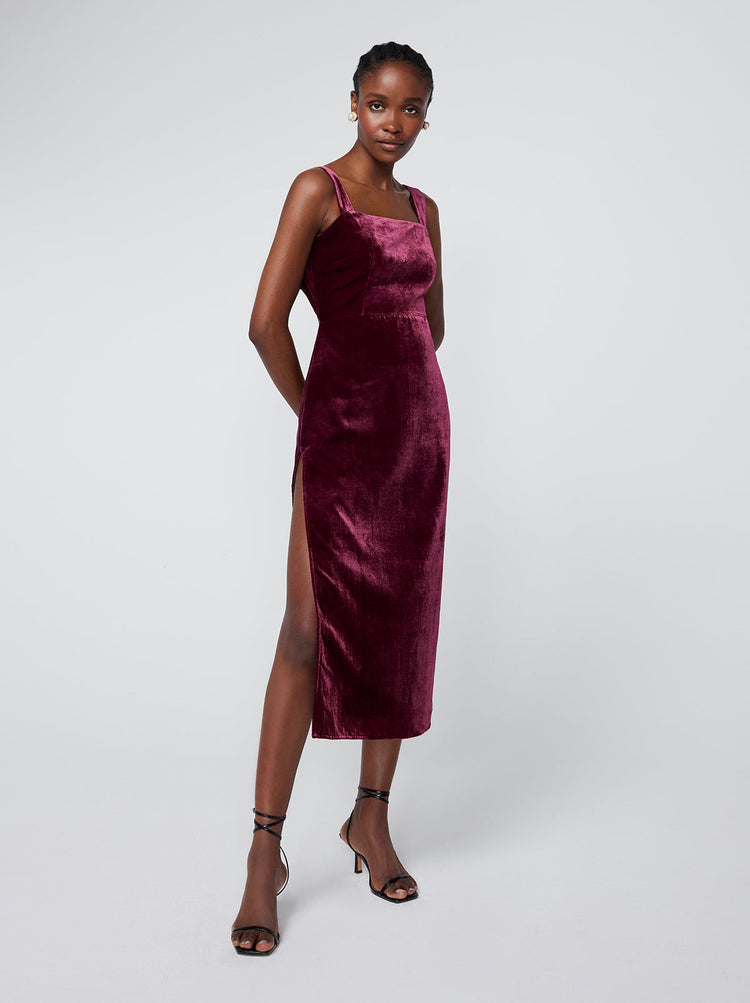 Aretha Burgundy Velvet Dress By KITRI Studio in a deep burgandy/maroon velvet fabric. A sultry midi length party dress ideal for Christmas/festive parties and other occasions. Featuring wide straps, open back detail and thigh split, this glamourous dress is as elegant as it is flattering. Best paired with stilletoes