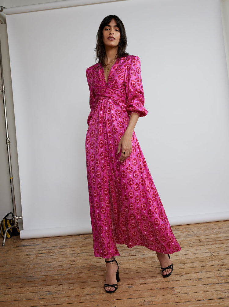 Aurora Pink Heart Print Maxi Dress By KITRI Studio is our bestselling, trending dress. A maxi party dress bursting with 70s style with its standout retro pink hearts printed fabric has voluminous flowy sleeves & cross-cross ribbon tie belt. A longline floaty summer dress, ideal for weddings and special occasions - as well as a popular pregnancy dress option