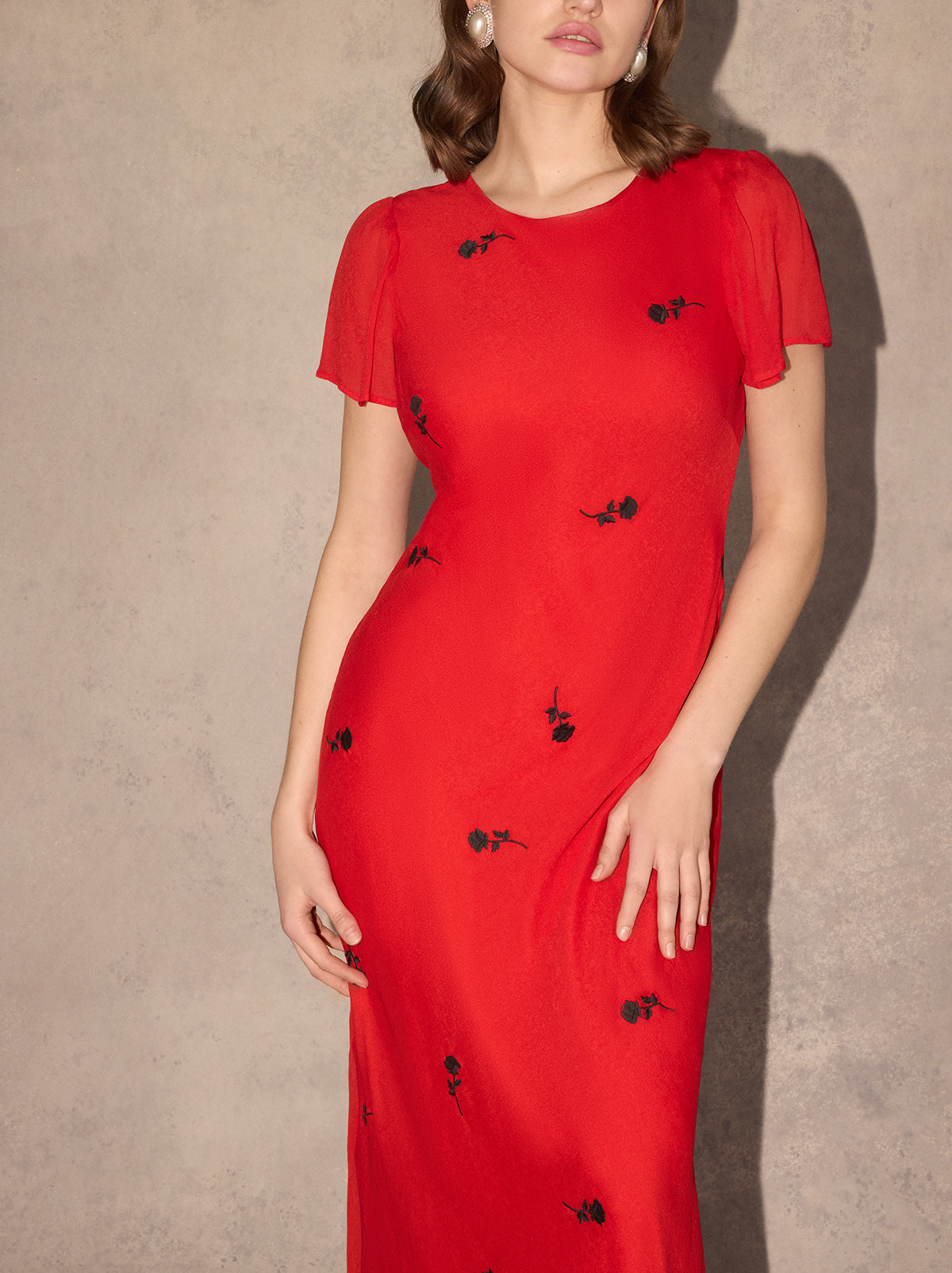 Marie Red Rose Embroidered Dress - Marie is a bias-cut midi dress featuring a flattering, figure-skimming skirt and cap sleeves for elegant coverage. Her lightweight georgette fabrication adds a tactile feel to the solid colour, with all-over contrast black rose embroidery.