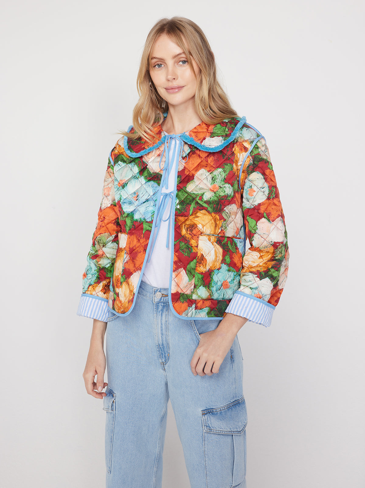 Piper Blue Impressionist Floral Print Reversible Quilted Jacket By KITRI Studio is a bestseller. This popular reversible jacket features a quilted multicoloured impressionist floral pattern on one side and baby blue pinstripes on the other - with front lace ties, large pockets and a relaxed fit. Your new favourite lightweight casual jacket