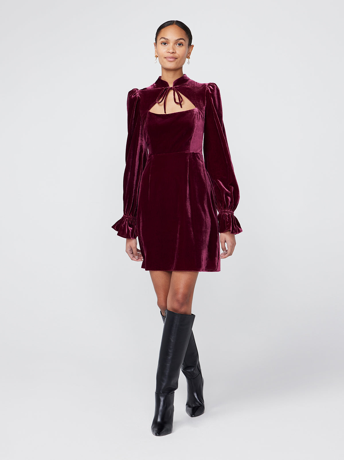 Valentina Burgundy Velvet Mini Dress By KITRI Studio is a sultry sleeved mini dress with a tie detail collar. An ideal party dress option it features puff shoulders and elasticated frilly cuffs - as well as a fitted bodice for a memorable silhouette. Deep dark red velvet fabric looks elegant and expensive.